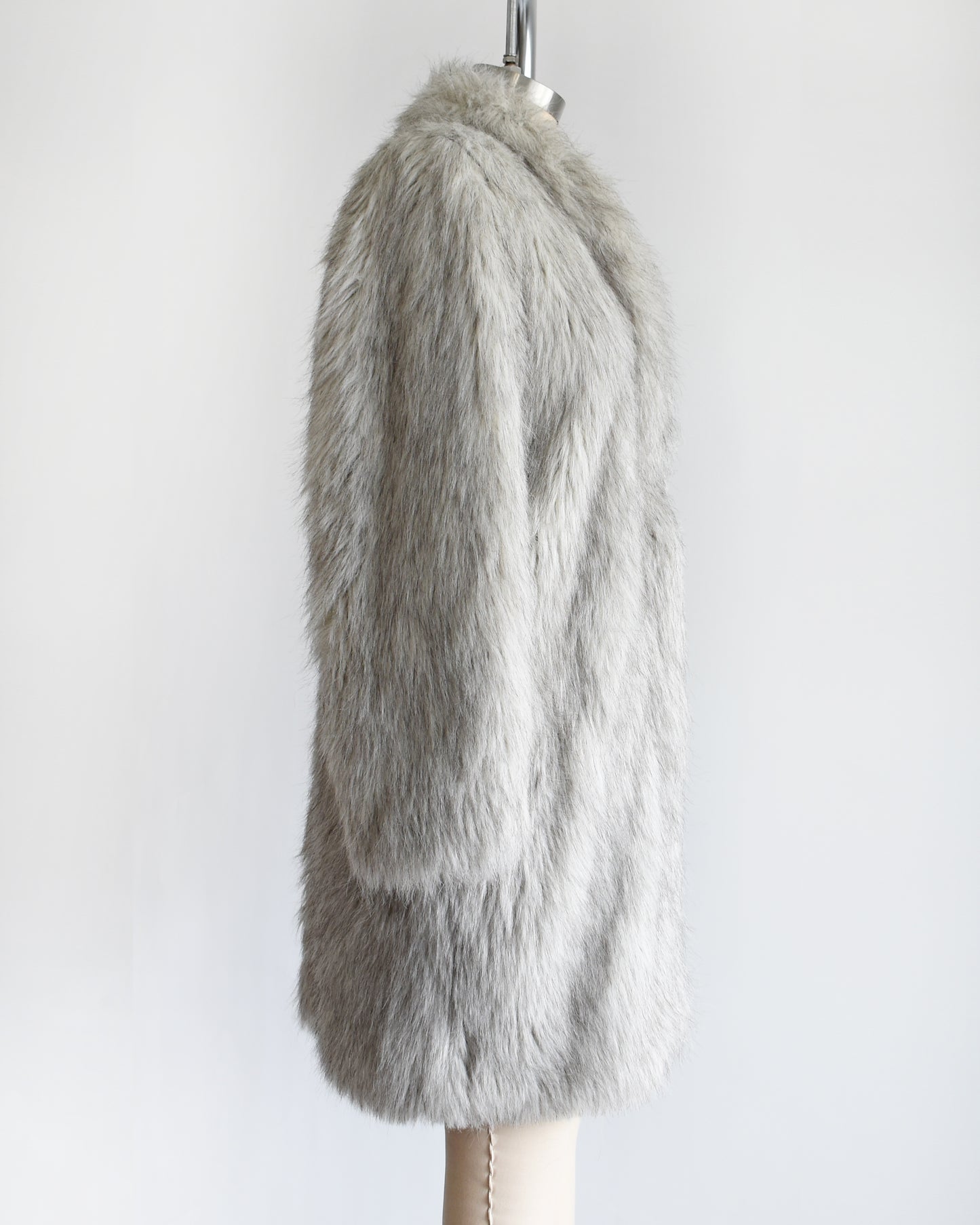 side view of a vintage 1980s faux fur silver fox coat  on a dress form on a white background