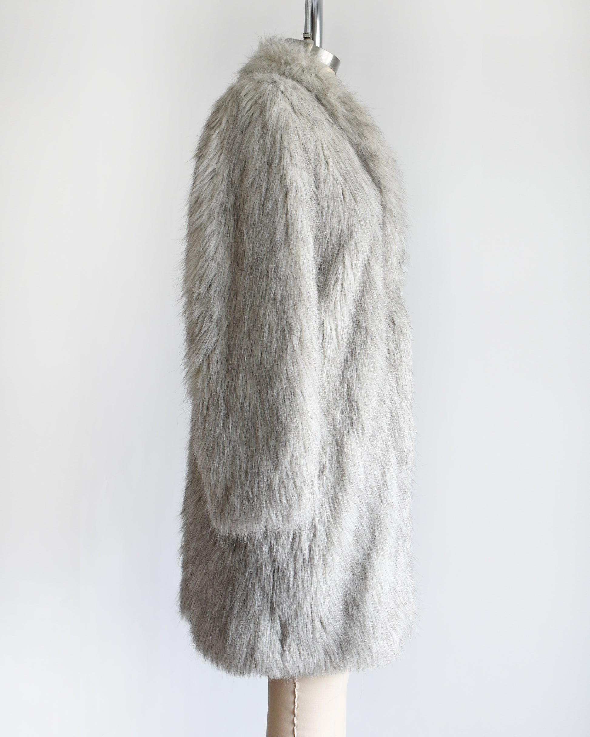 side view of a vintage 1980s faux fur silver fox coat  on a dress form on a white background