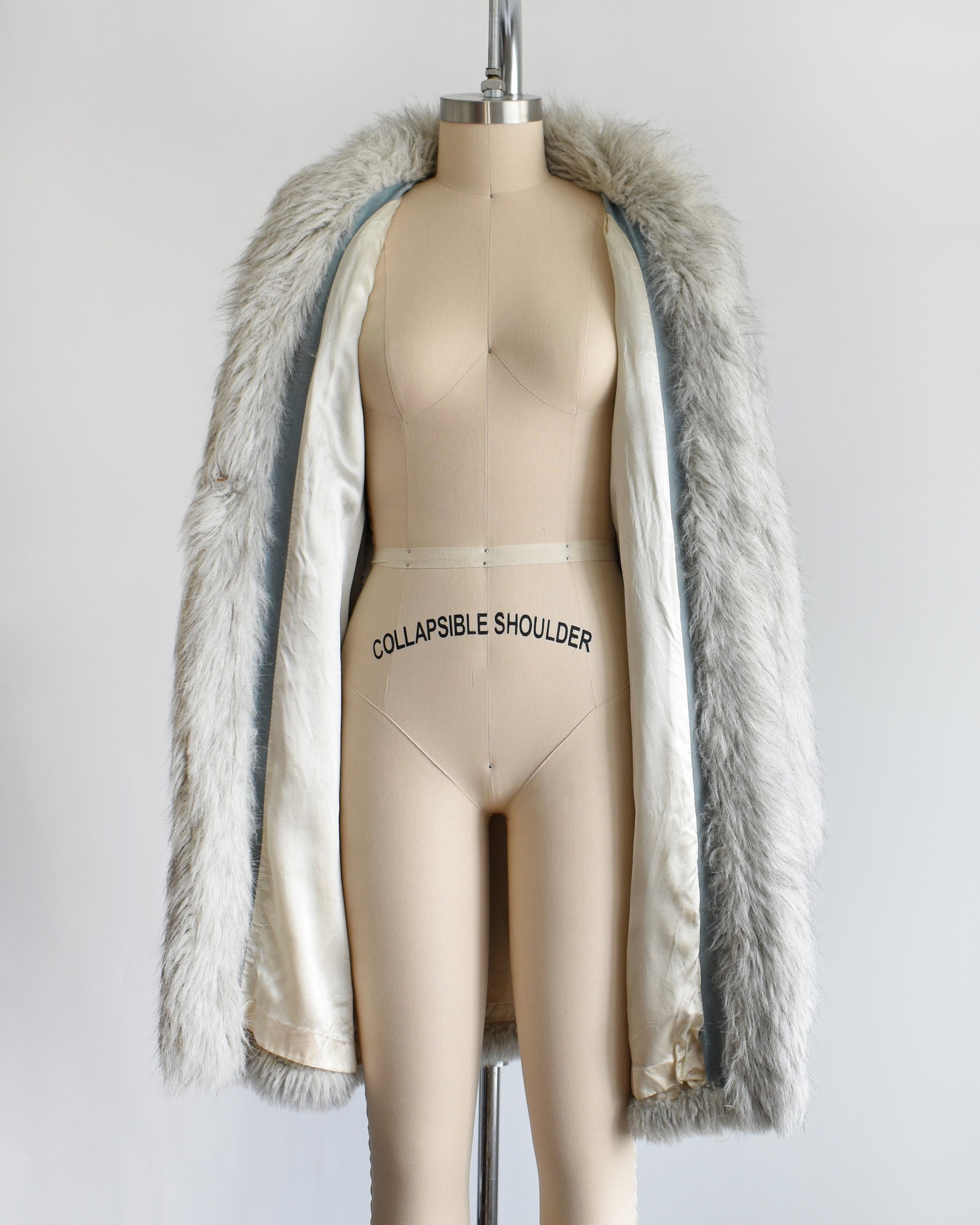a vintage 1980s faux fur silver fox coat  on a dress form on a white background. the coat is open, showing the lining