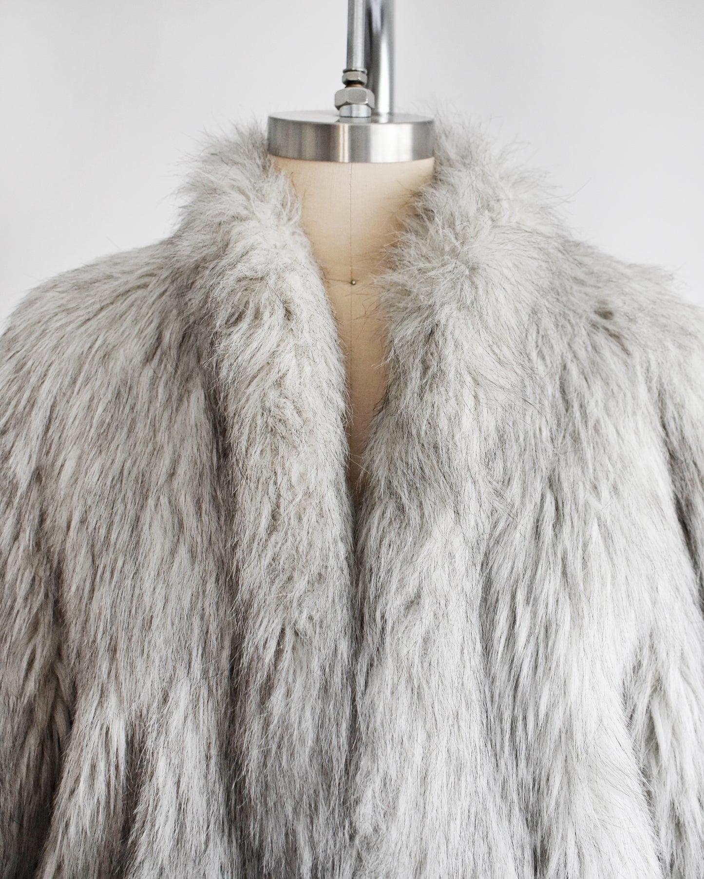 close up of the collar on a vintage 1980s faux fur silver fox coat  on a dress form on a white background