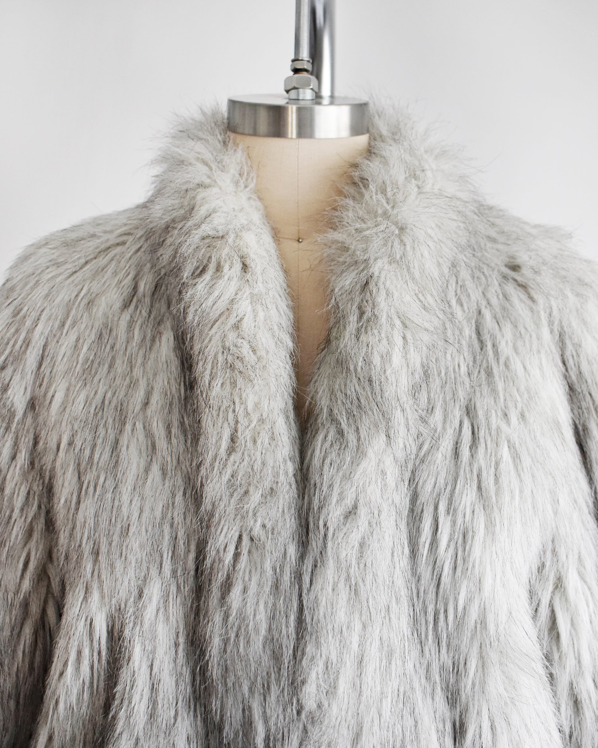 close up of the collar on a vintage 1980s faux fur silver fox coat  on a dress form on a white background