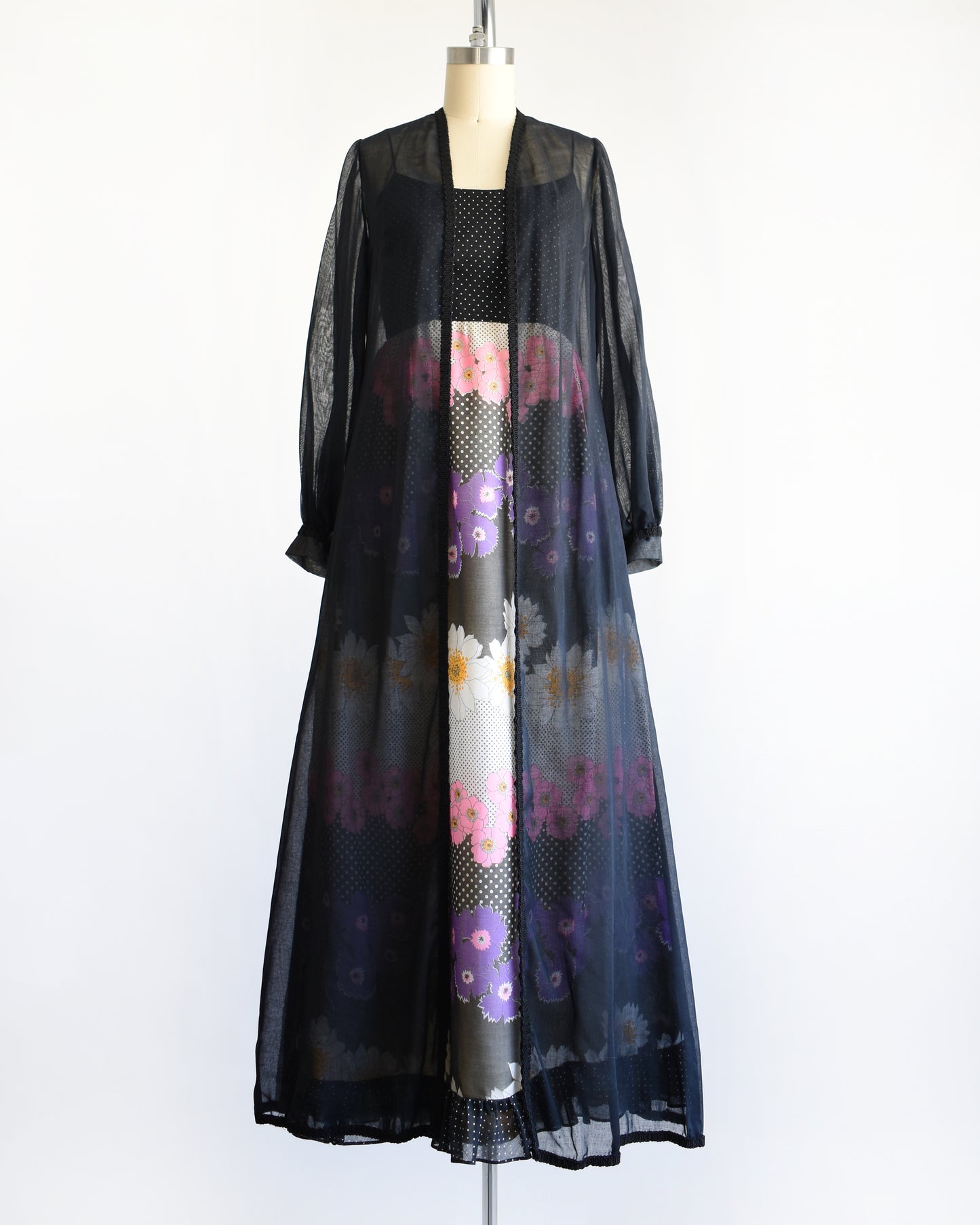 a vintage 1970s black floral dress with black duster on a mannequin against a white background
