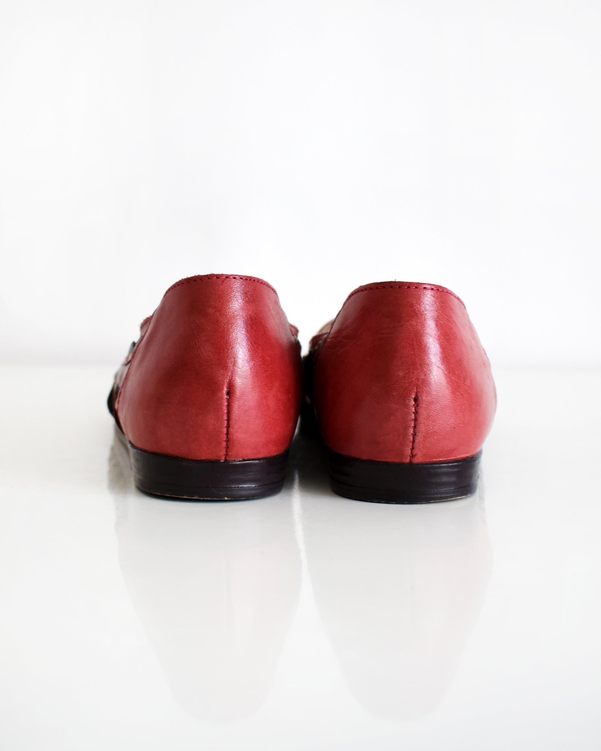 the back of a pair of vintage 1980s women's pointed-toe flat shoes featuring a red backs, shown on a plain white background.