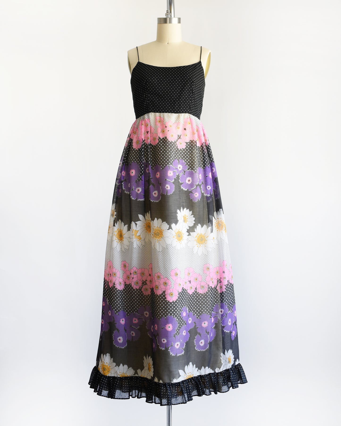 a vintage 1970s black floral dress on a mannequin against a white background