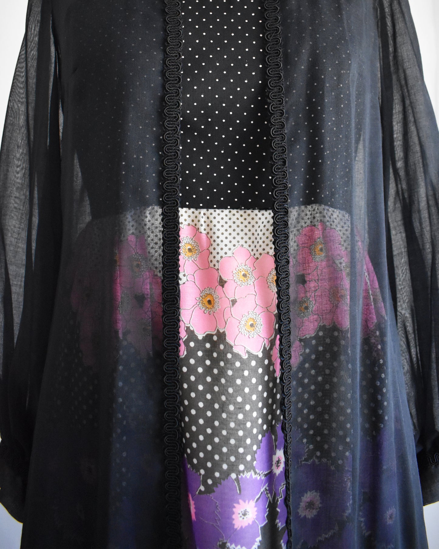 close up of a vintage 1970s black floral dress with black duster on a mannequin against a white background