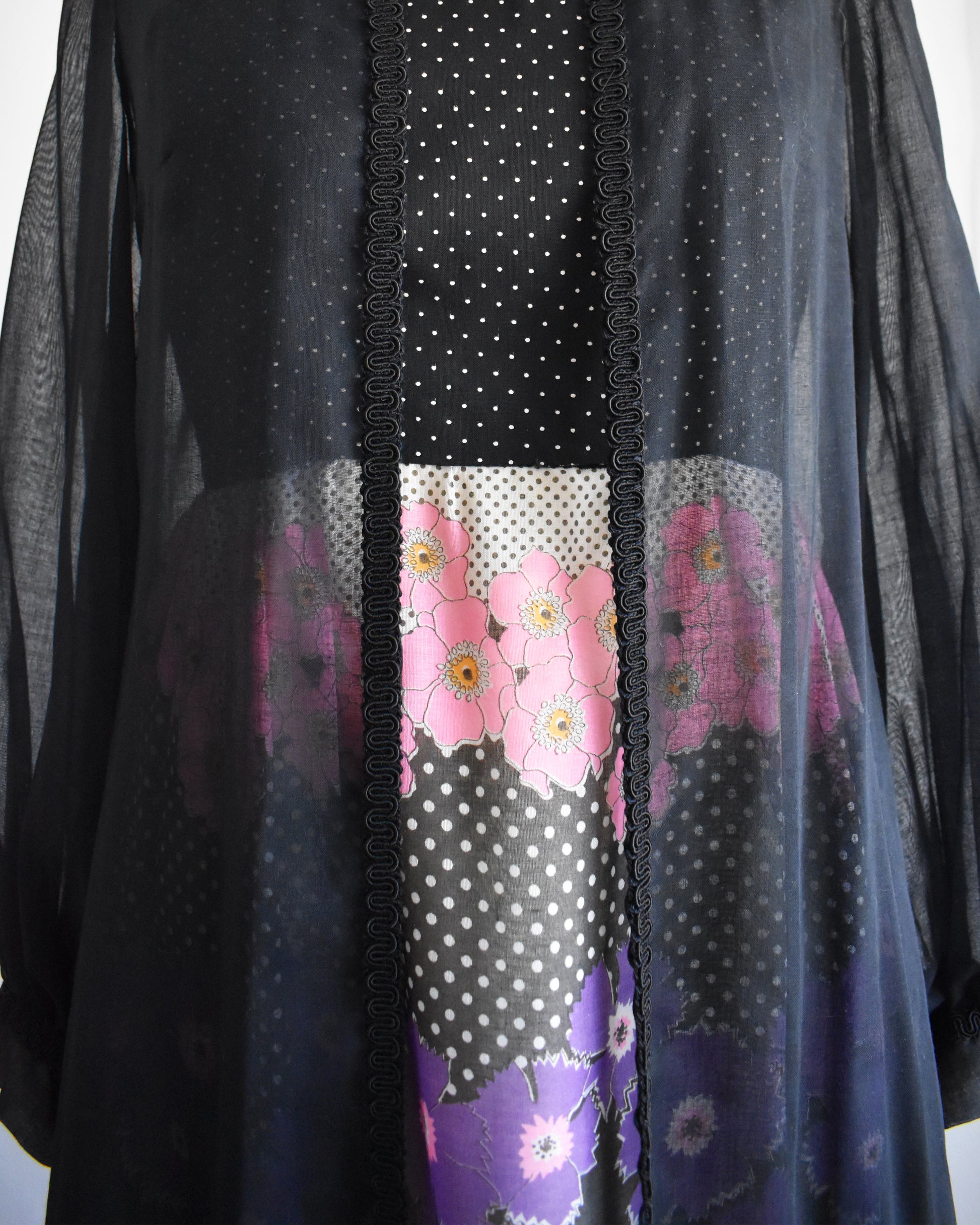 close up of a vintage 1970s black floral dress with black duster on a mannequin against a white background