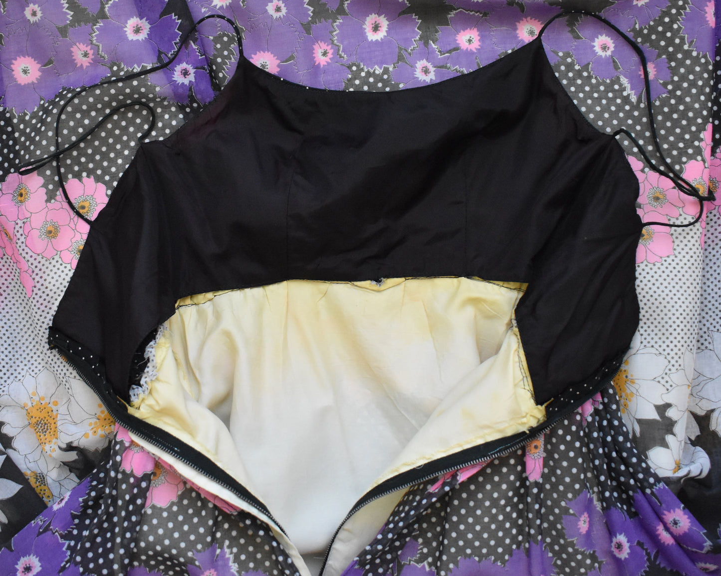 a vintage 1970s black floral dress that is zipped open showing the lining