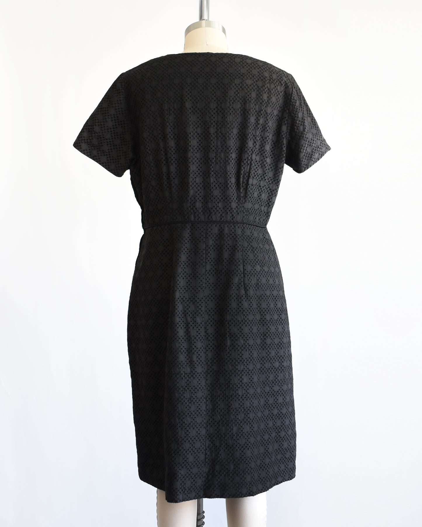 back view of a vintage 1960s black eyelet dress on a mannequin on a dress form