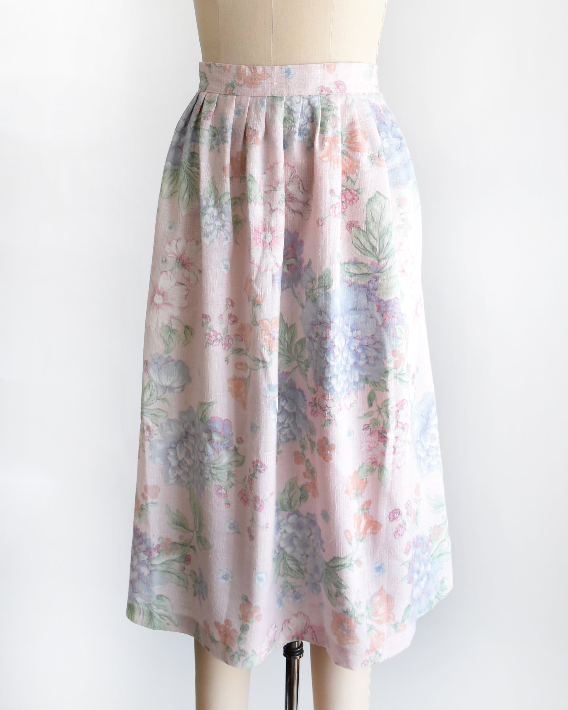 side front view of a vintage 1980s  high-waisted midi skirt with a pastel floral print, displayed on a beige dress form mannequin against a plain white background.
