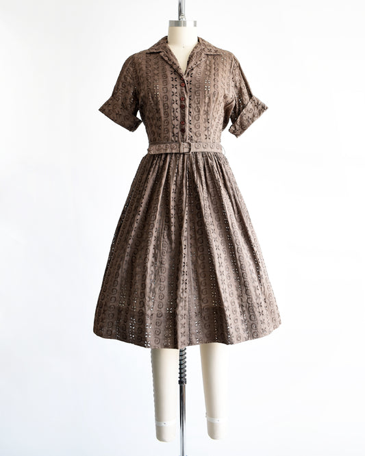 a  vintage 1950s brown eyelet shirt dress with belt on a dress form