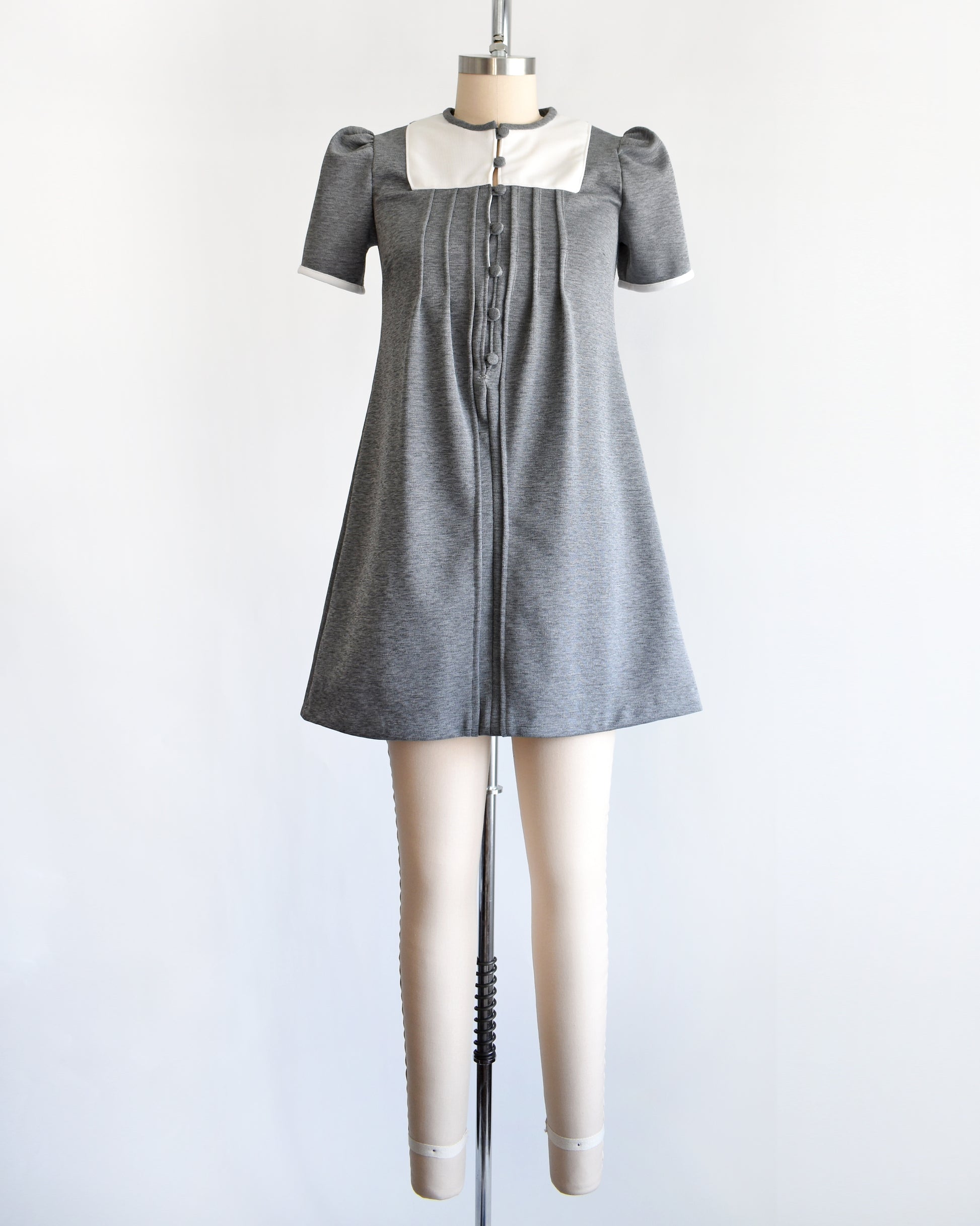 a vintage 1960s gray dress with white collar on a mannequin against a white background