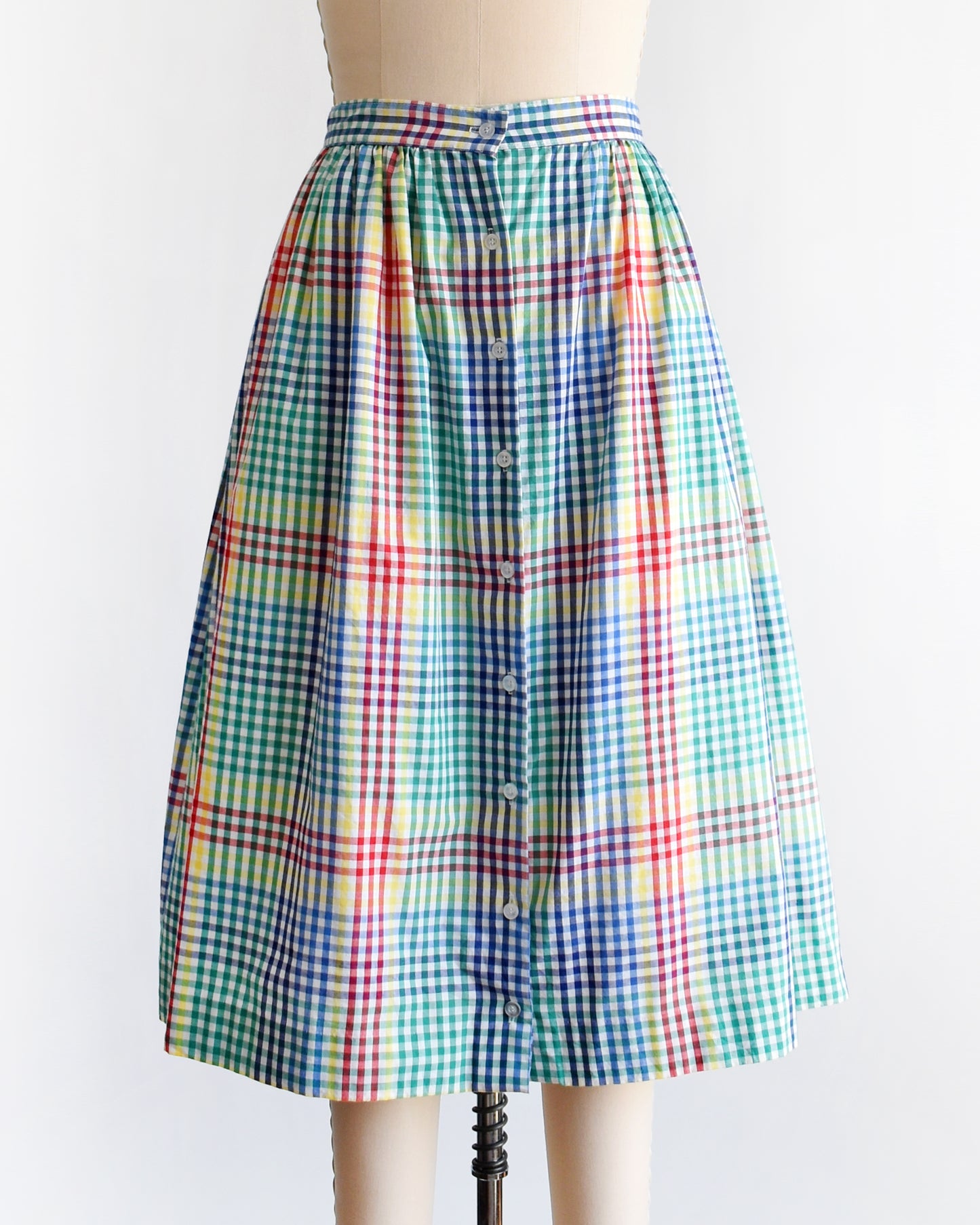 a vintage 1980s multicolor plaid midi skirt displayed on a beige dress form mannequin against a plain white background.