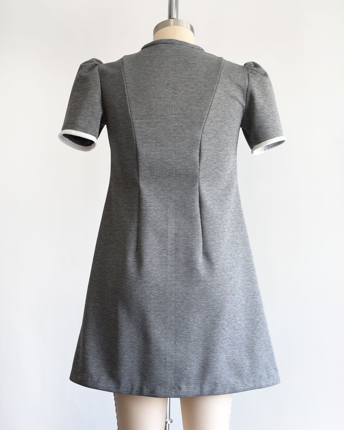 back view of a vintage 1960s gray dress with white collar on a mannequin against a white background