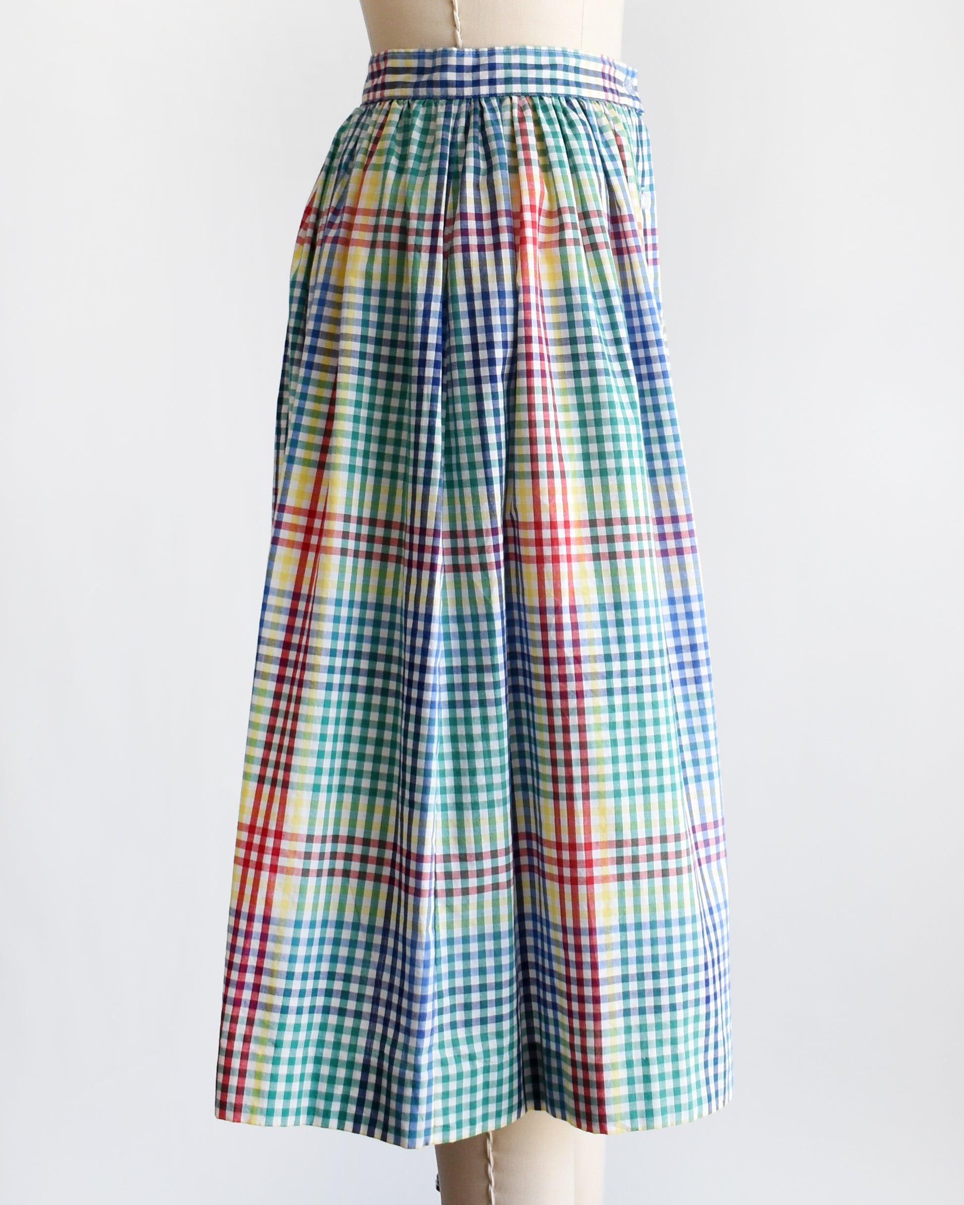side view of a vintage 1980s multicolor plaid midi skirt displayed on a beige dress form mannequin against a plain white background.
