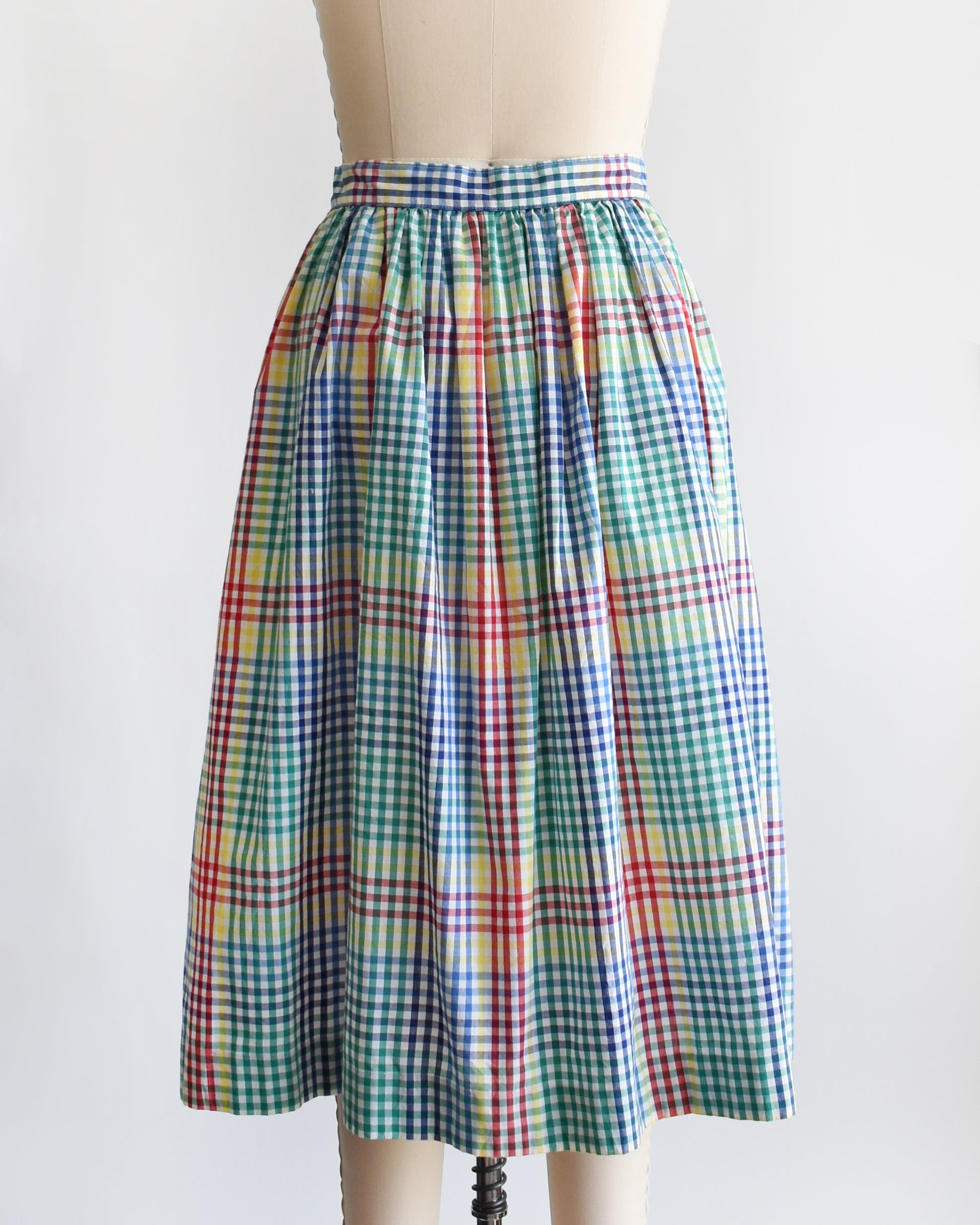 back view of a vintage 1980s multicolor plaid midi skirt displayed on a beige dress form mannequin against a plain white background.