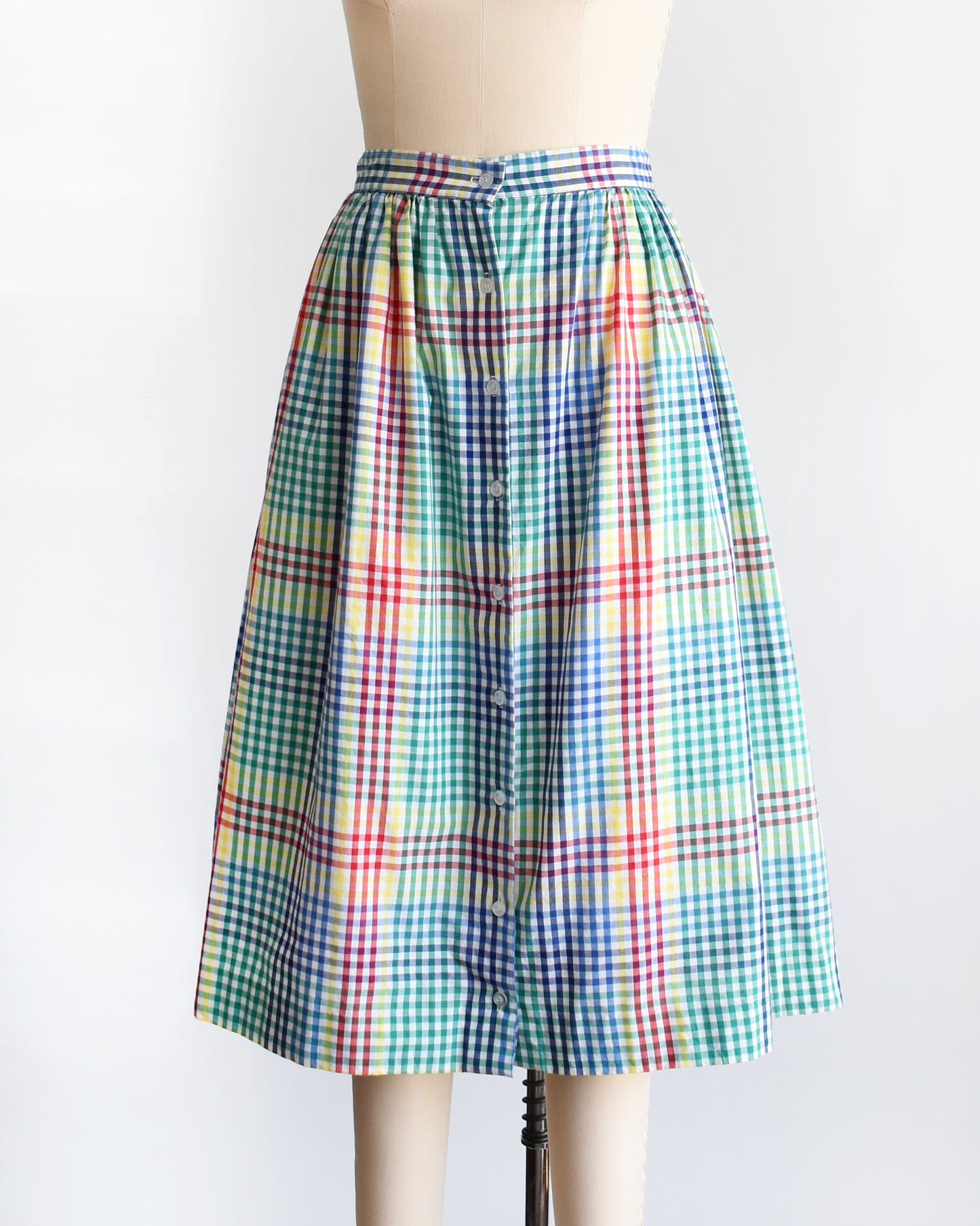 side front view of a vintage 1980s multicolor plaid midi skirt displayed on a beige dress form mannequin against a plain white background.