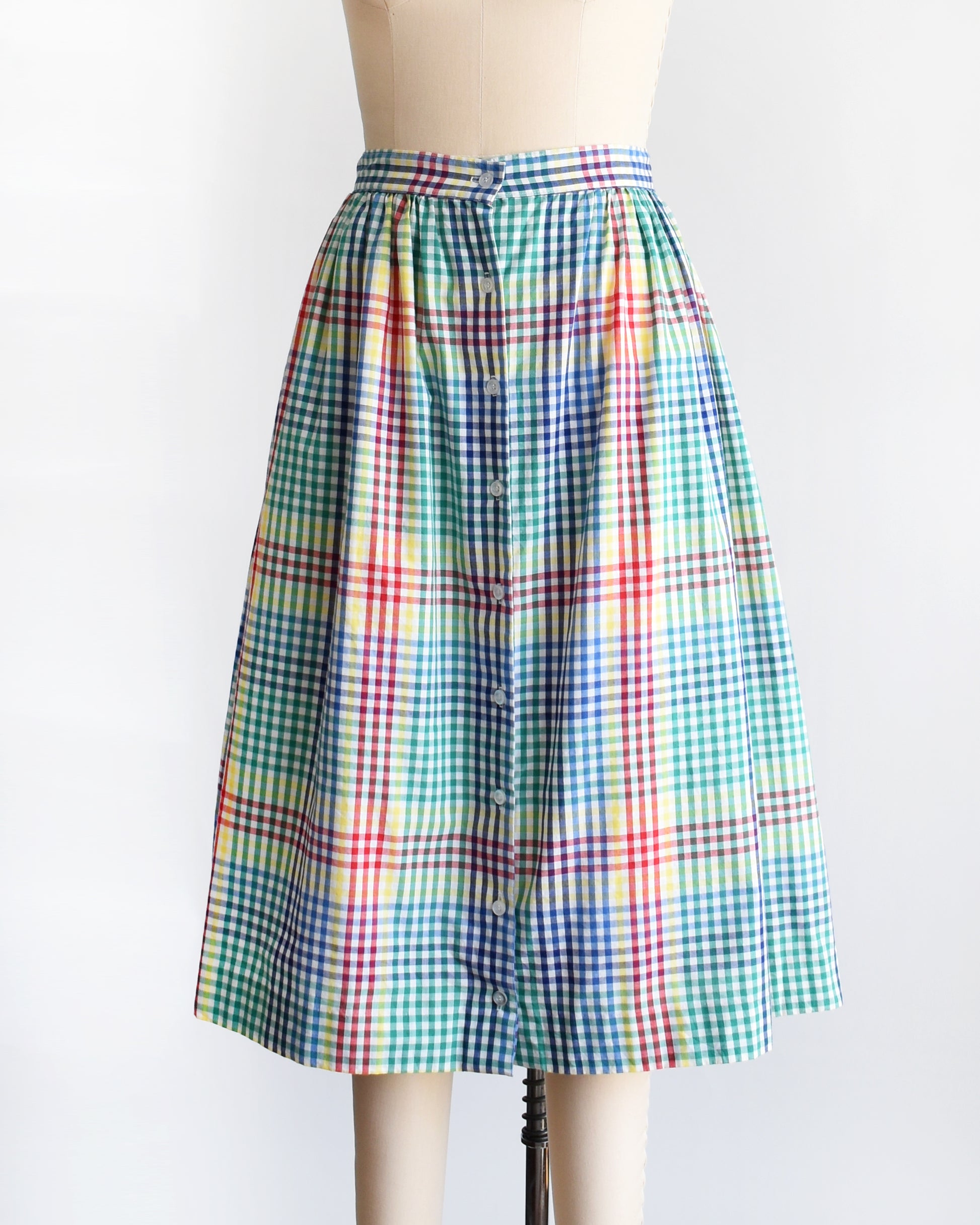 side front view of a vintage 1980s multicolor plaid midi skirt displayed on a beige dress form mannequin against a plain white background.