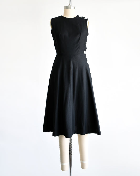 a vintage 1960s black cotton dress with buttons down the left side on a dress form