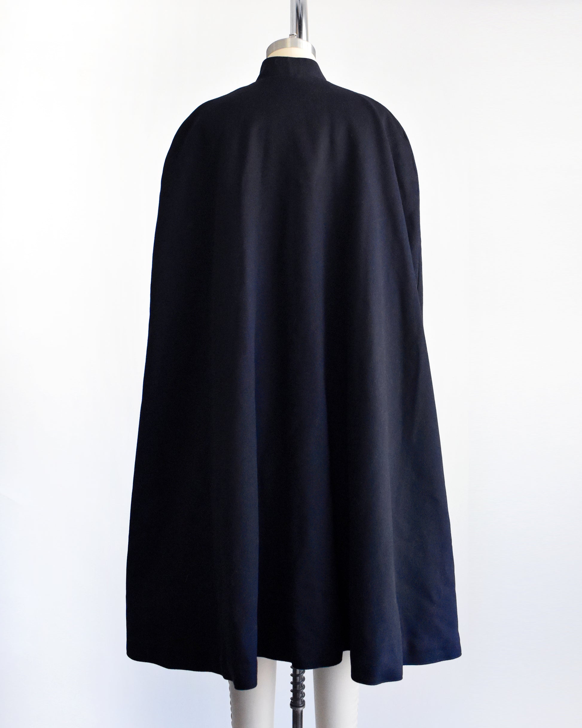 back view of a vintage 1940s navy nurse's cape on a mannequin against a white background. 