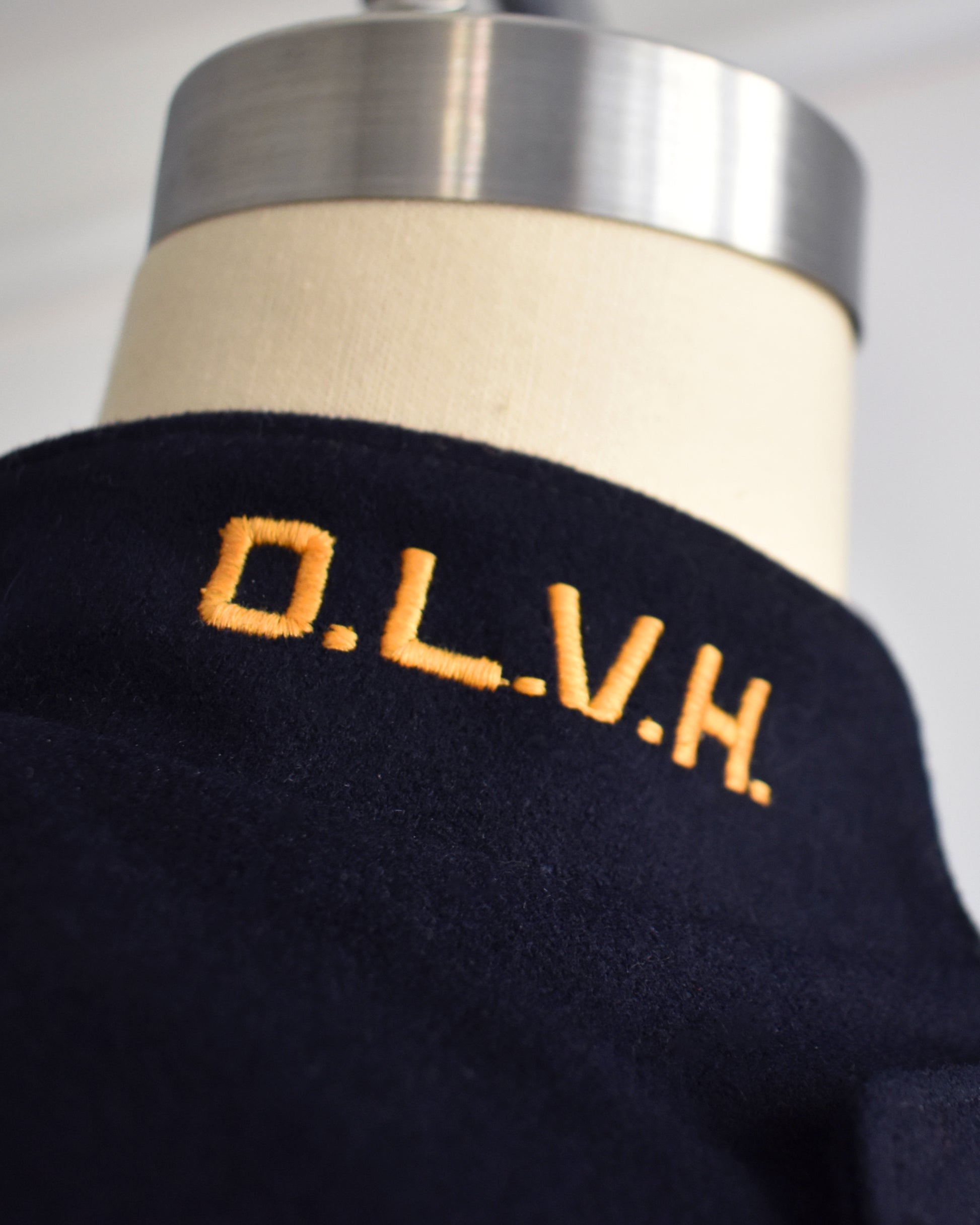 close up of the monogram O.L.V.H on the side of the collar