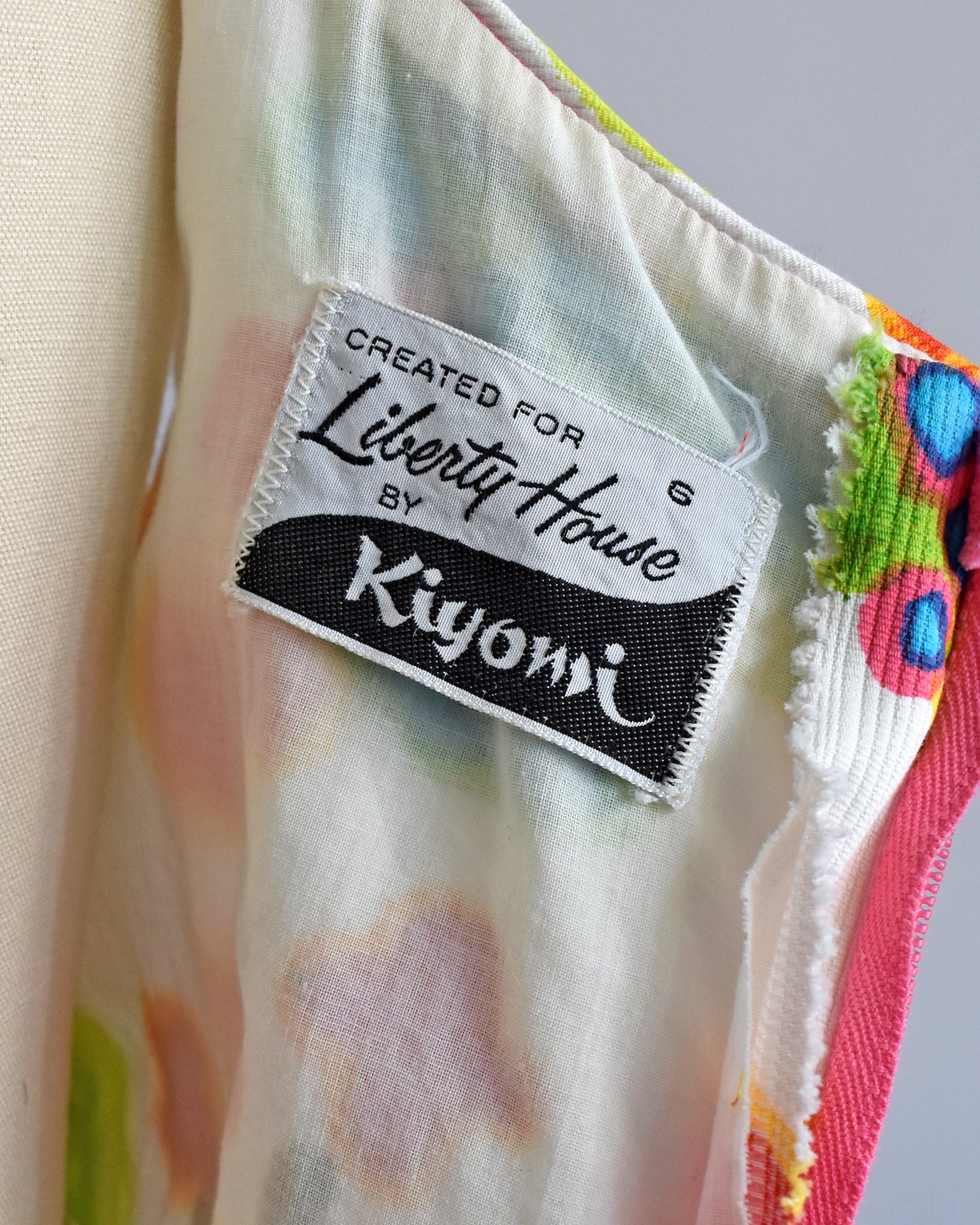 Close-up of the label inside the dress that says 'Created for Liberty House by Kiyomi' on a cream-colored fabric with a multicolor floral print.