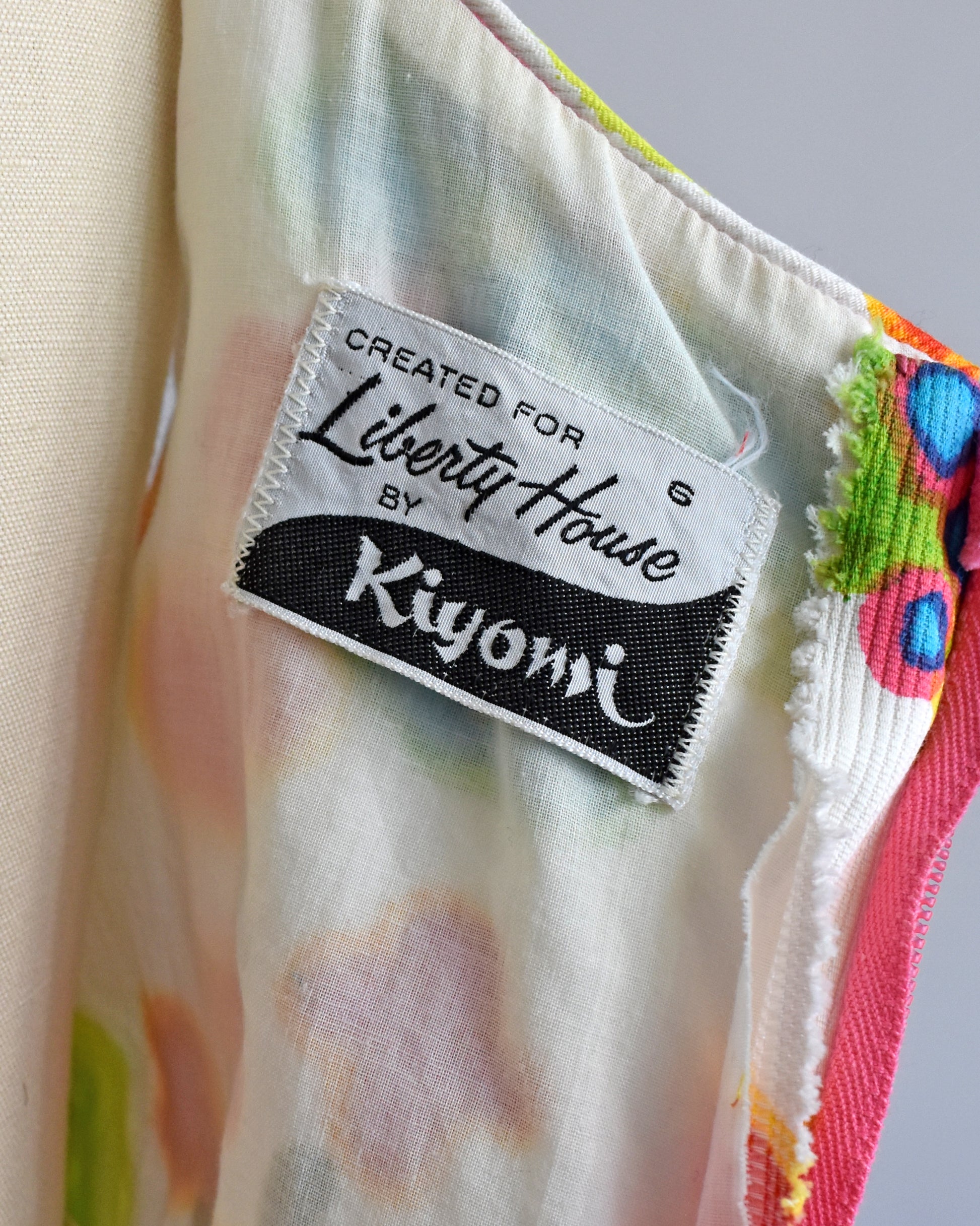 Close-up of the label inside the dress that says 'Created for Liberty House by Kiyomi' on a cream-colored fabric with a multicolor floral print.