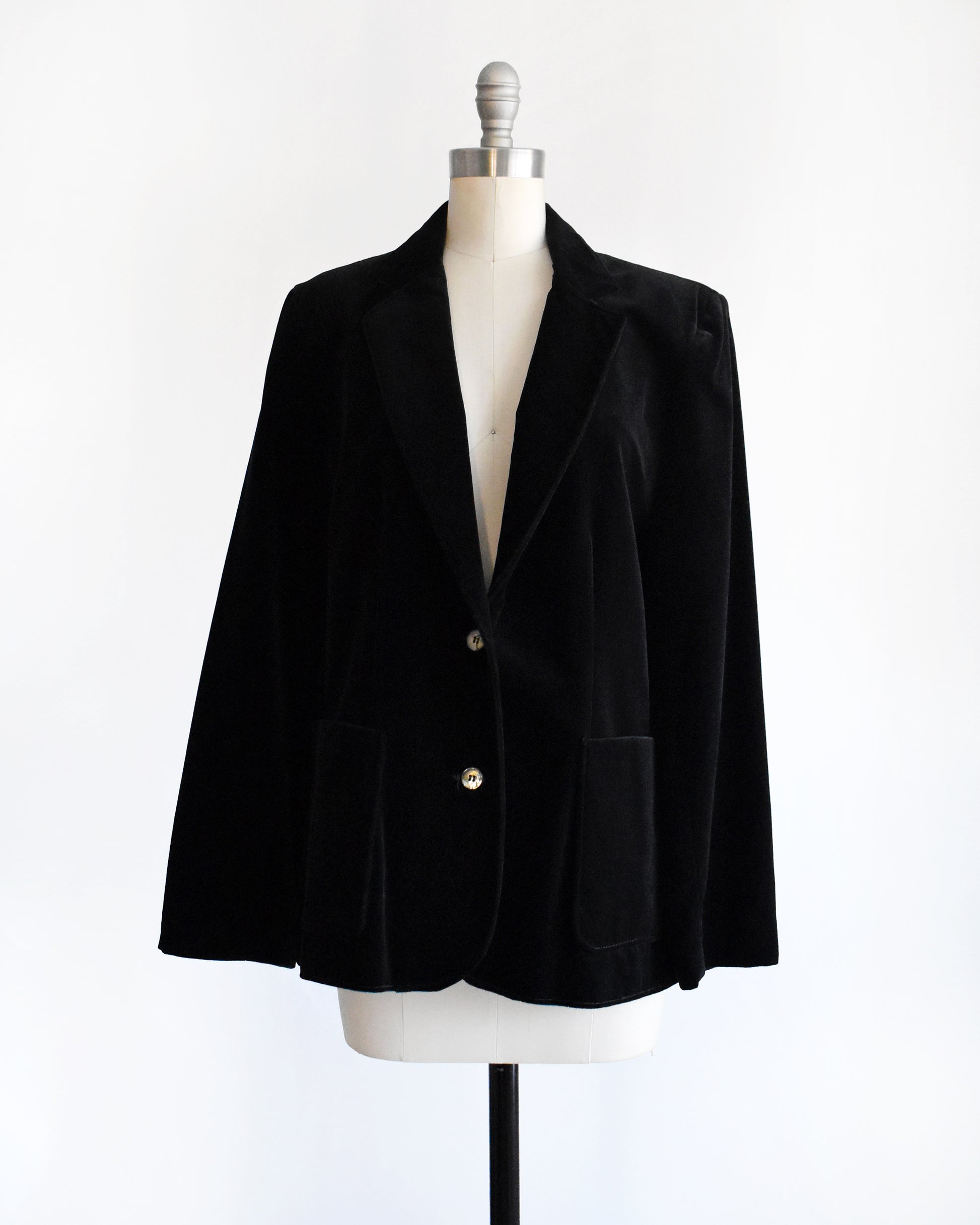 a vintage 1980s black velvet  blazer on a mannequin against a white background