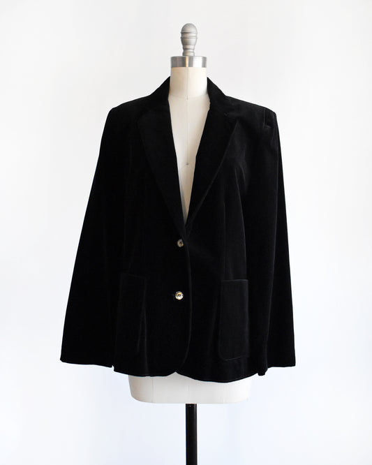 a vintage 1980s black velvet  blazer on a mannequin against a white background