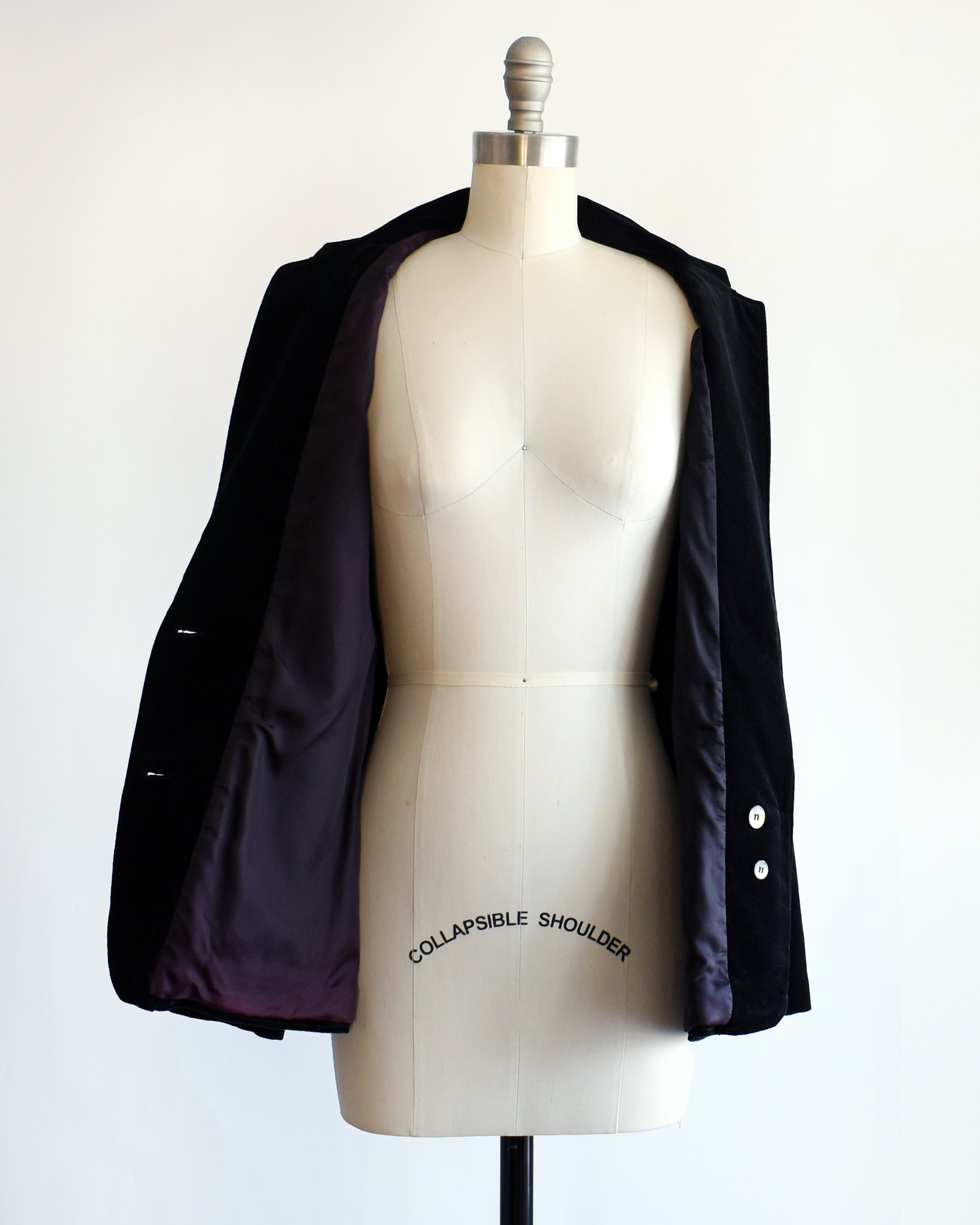 a vintage 1980s black velvet  blazer on a mannequin against a white background. the blazer is unbuttoned in this photo
