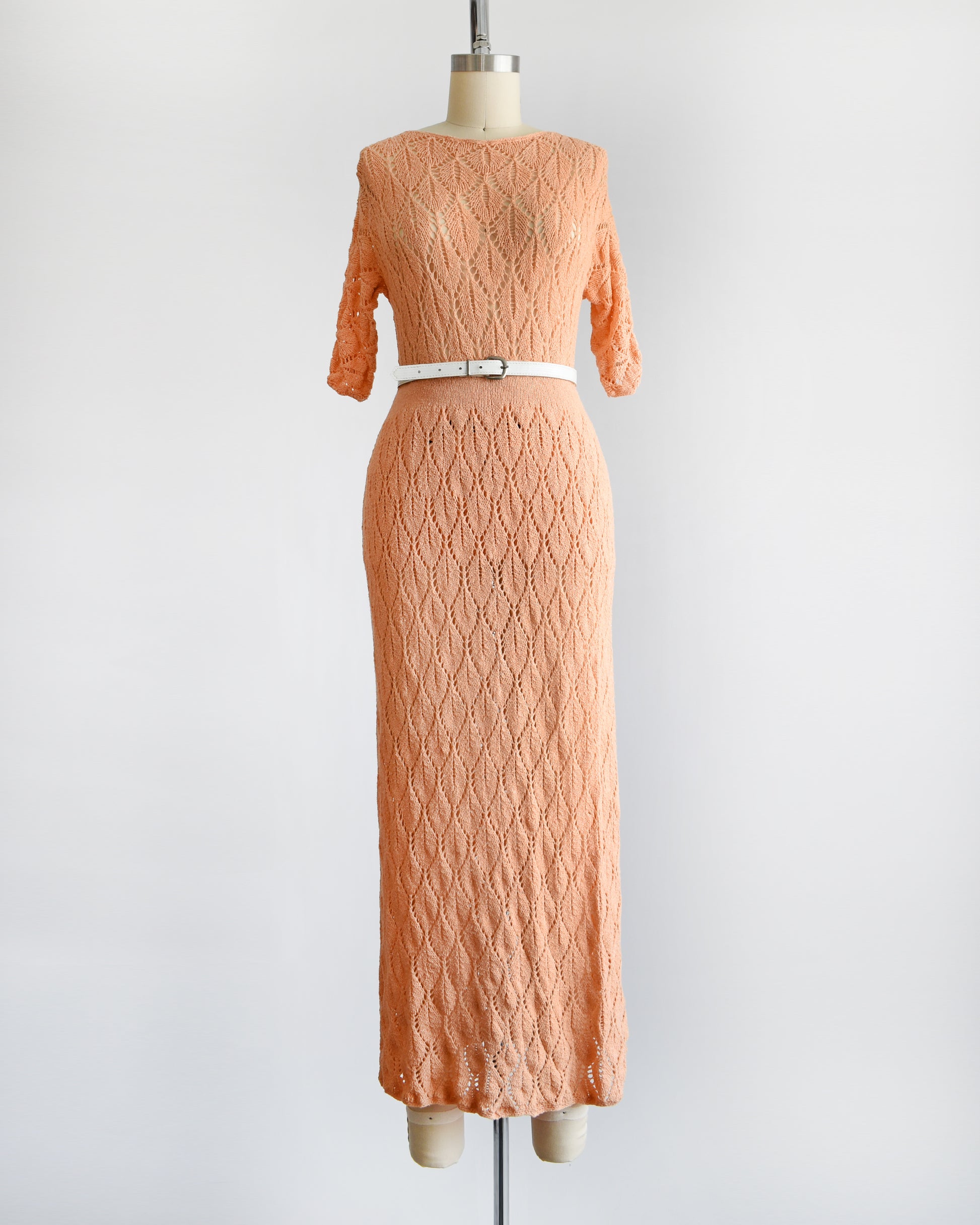 a vintage 60s peach pointelle knit sweater set which includes a matching sweater and maxi skirt. The set is shown with a white belt, which isn't included.