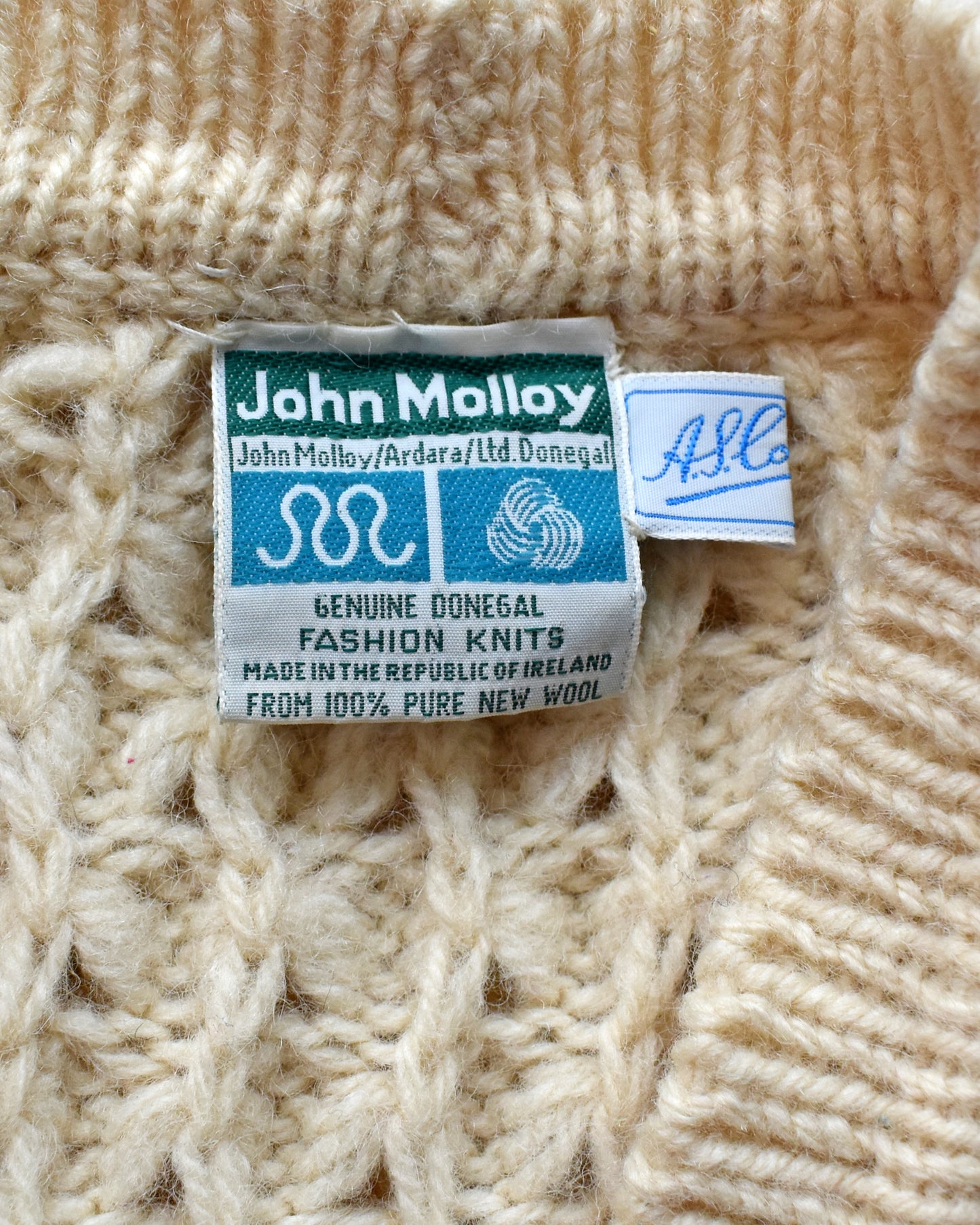 Close-up of a John Molloy label on a knitted fabric background