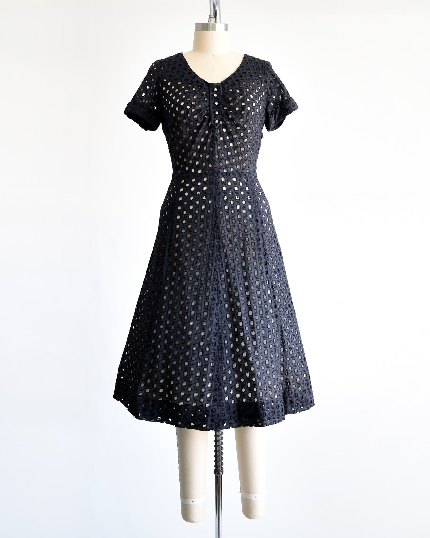 a vintage 1950s black eyelet dress that has 5 rhinestone buttons under the neckline