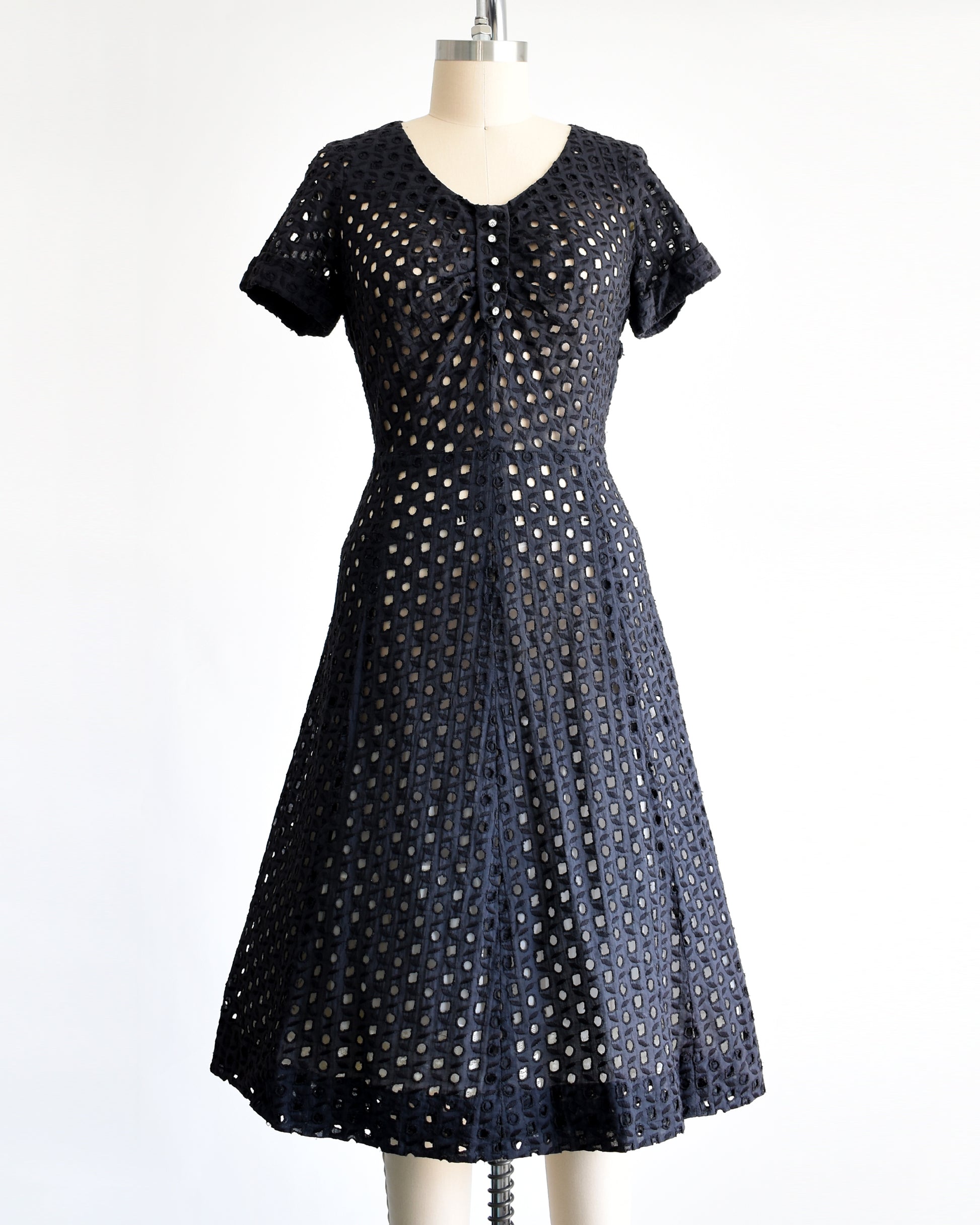 a vintage 1950s black eyelet dress that has 5 rhinestone buttons under the neckline