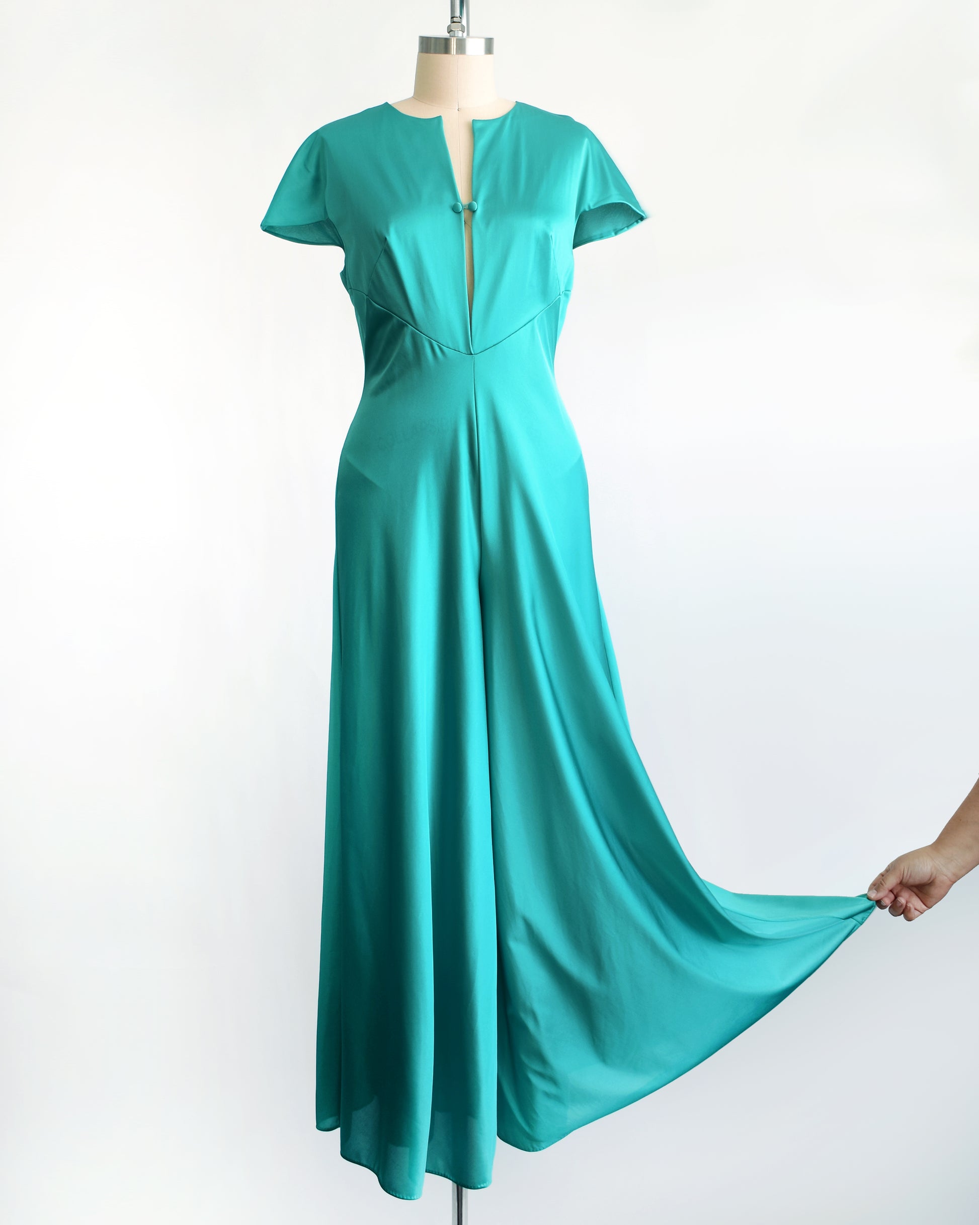 a vintage 1970s teal palazzo jumpsuit by Vanity Fair. The pants are being pulled to at the hem to show the sweep of the leg