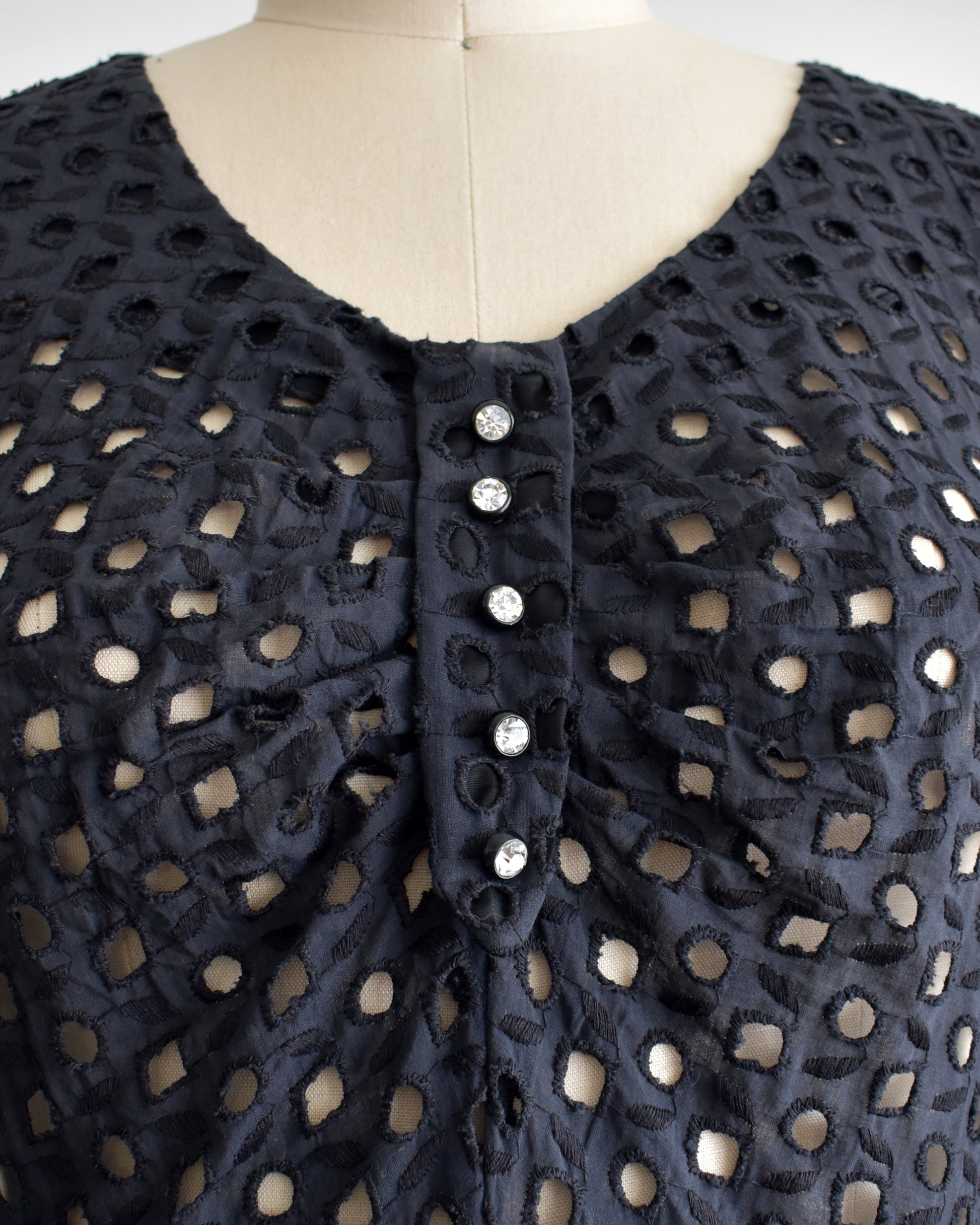 a close up of the bodice which shows the eyelet detail and the rhinestone buttons