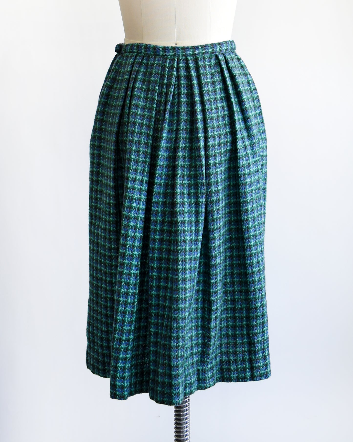 back view of a vintage 1950s/1960s blue and green plaid skirt on a mannequin against a white background