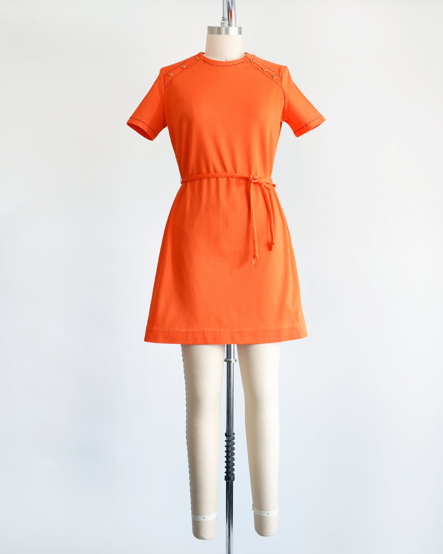 a vintage 1960s orange mod dress with black stitch trim on the front collar and shoulders, along with decorative gold buttons on the shoulder.