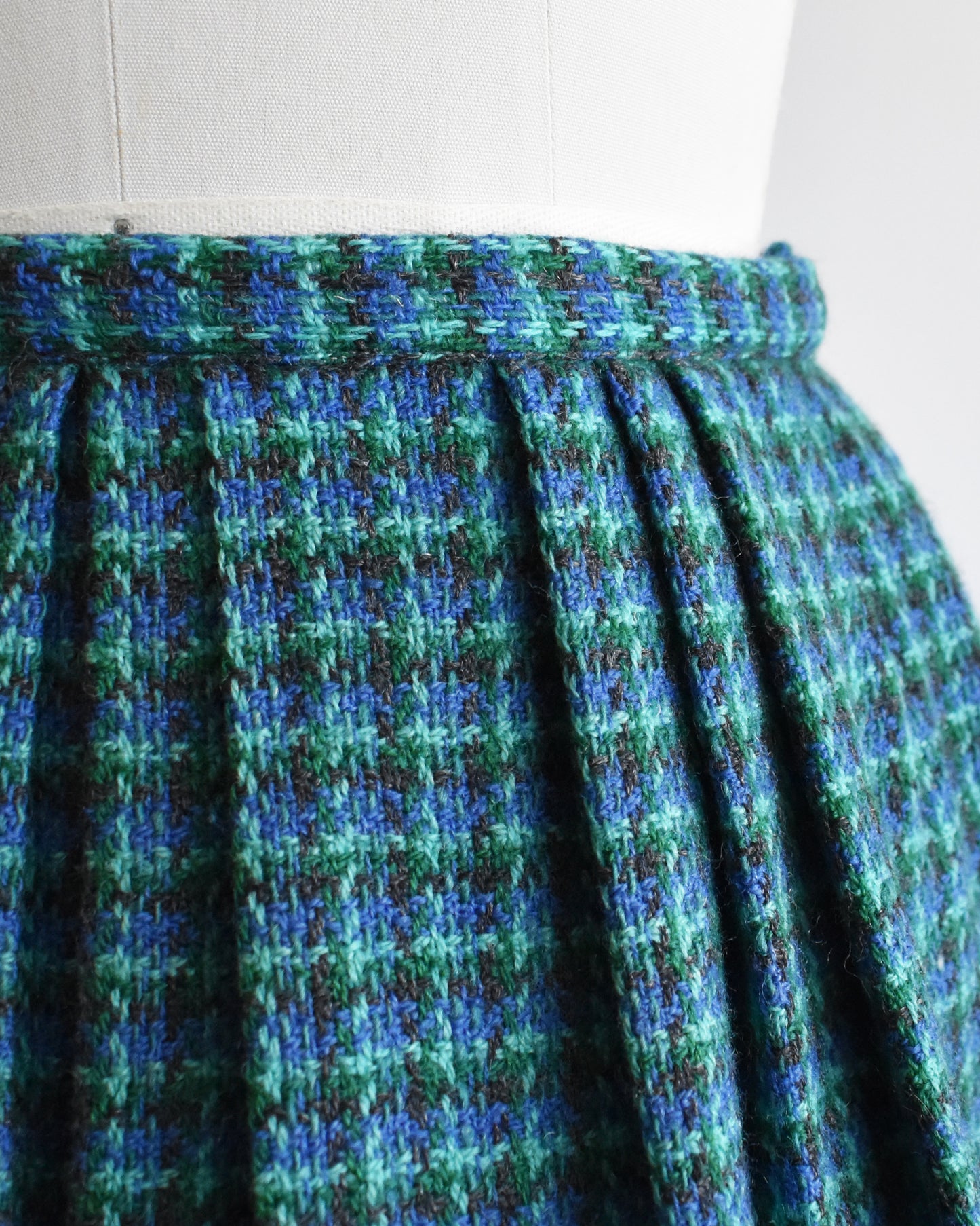 close up of the waist of a vintage 1950s/1960s blue and green plaid skirt on a mannequin against a white background