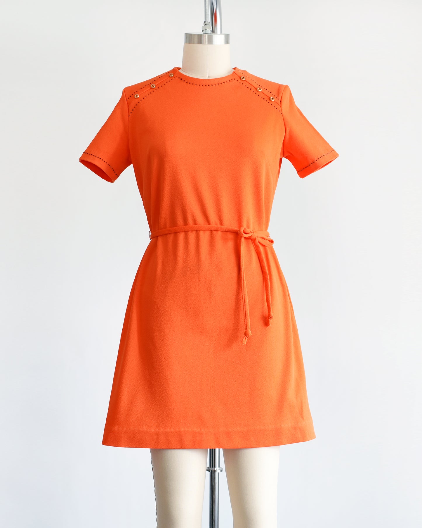 a vintage 1960s orange mod dress with black stitch trim on the front collar and shoulders, along with decorative gold buttons on the shoulder.