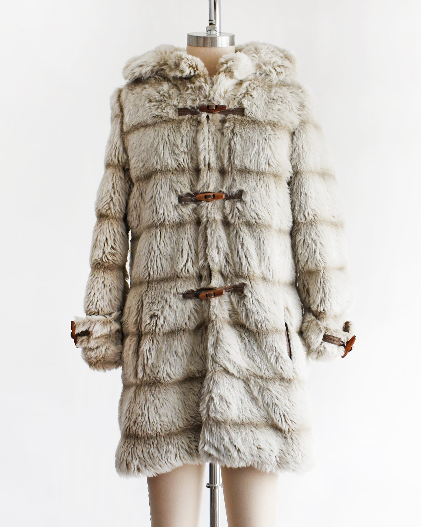 a vintage 1970s faux fur coat with hood on a mannequin against a white background