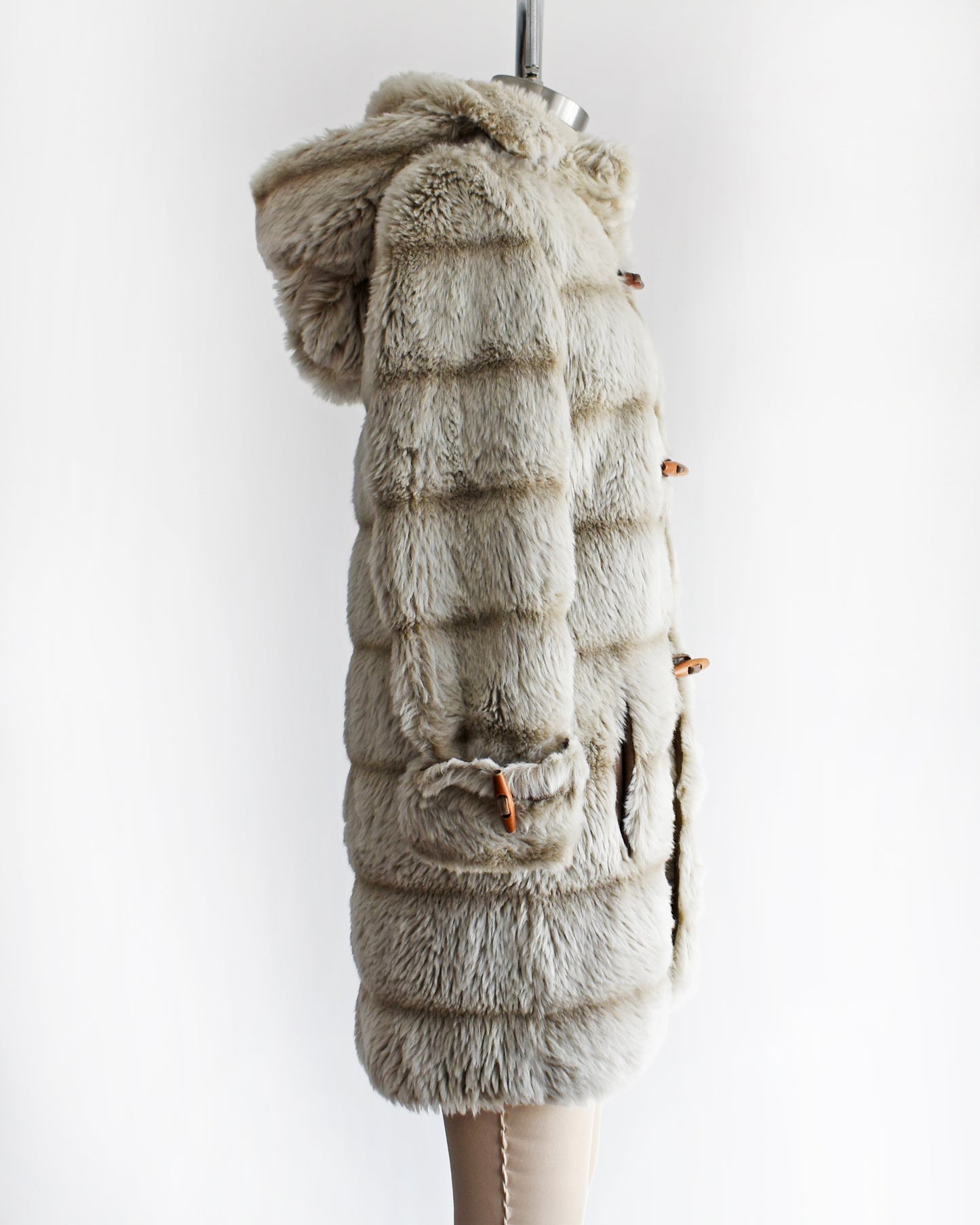 side view of a vintage 1970s faux fur coat with hood on a mannequin against a white background