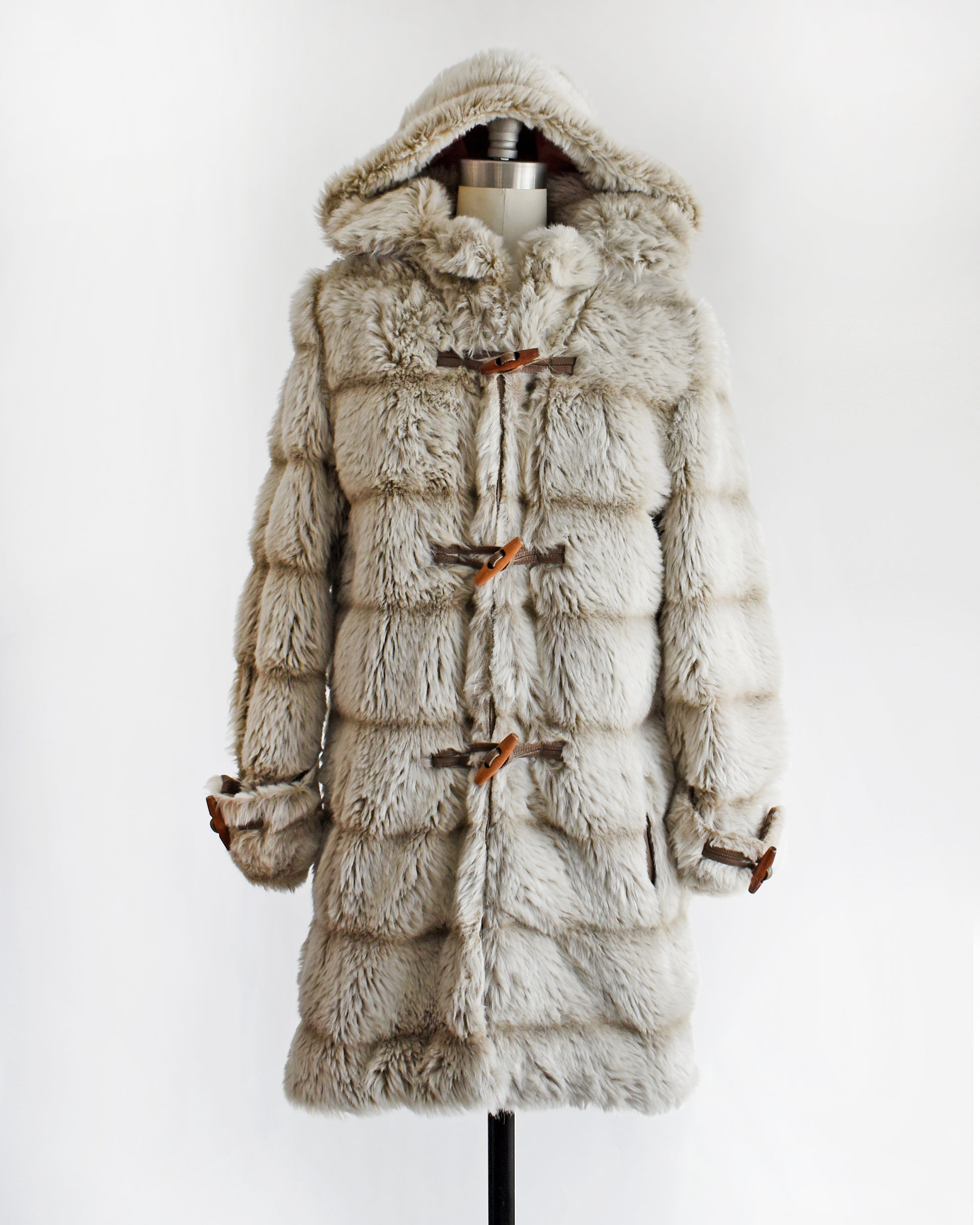 a vintage 1970s faux fur coat with hood on a mannequin against a white background