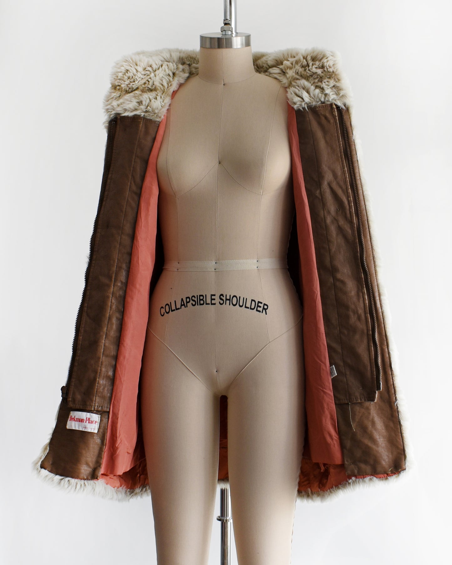 a vintage 1970s faux fur coat with hood on a mannequin against a white background. the coat is open in the photo