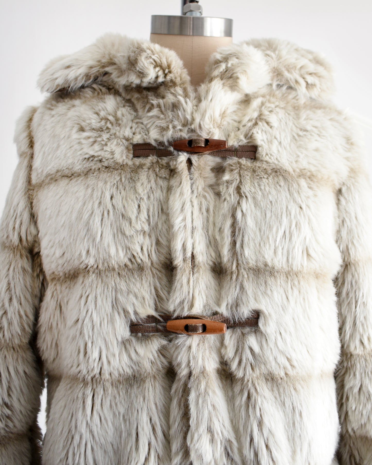 close up of a vintage 1970s faux fur coat with hood on a mannequin against a white background