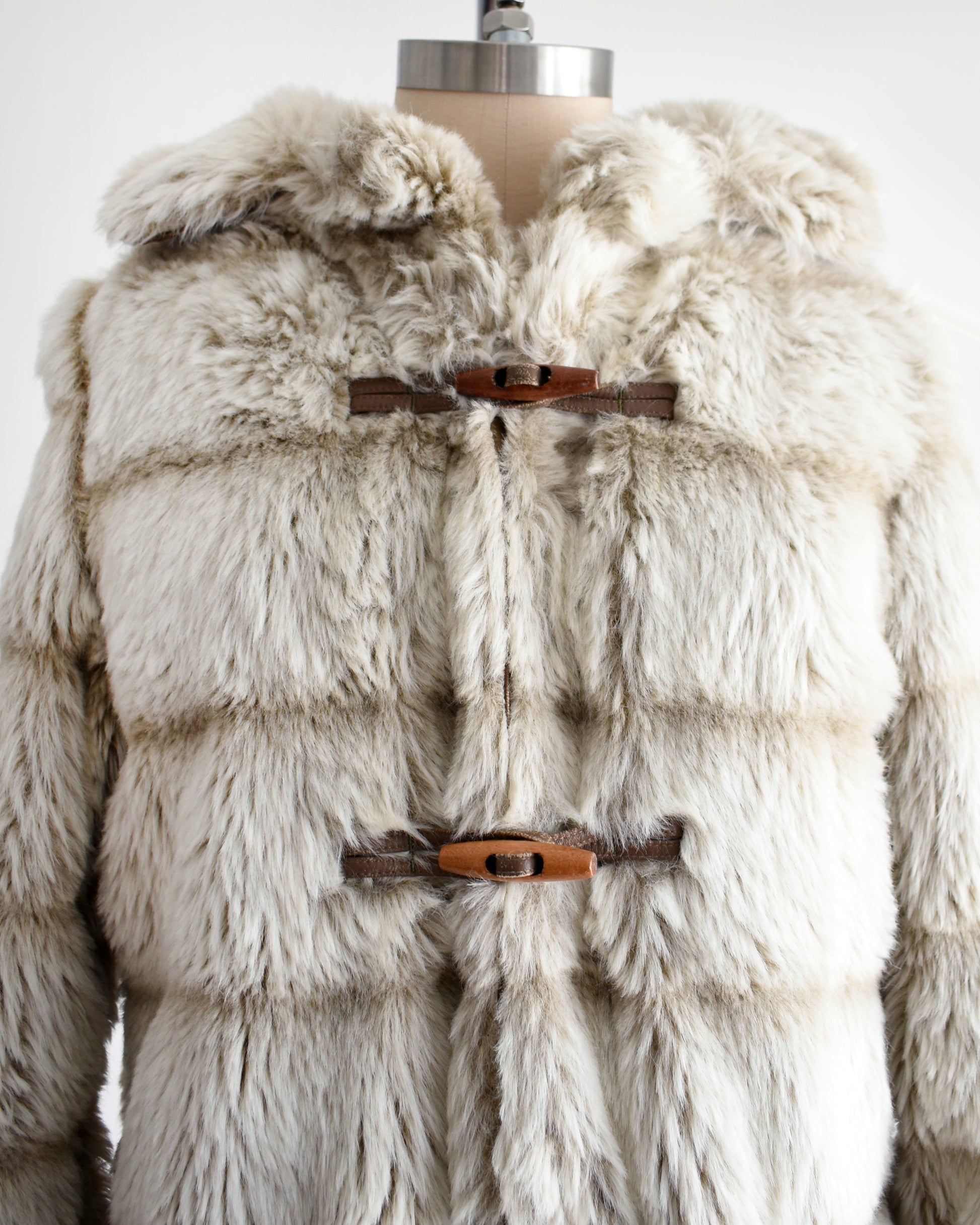close up of a vintage 1970s faux fur coat with hood on a mannequin against a white background