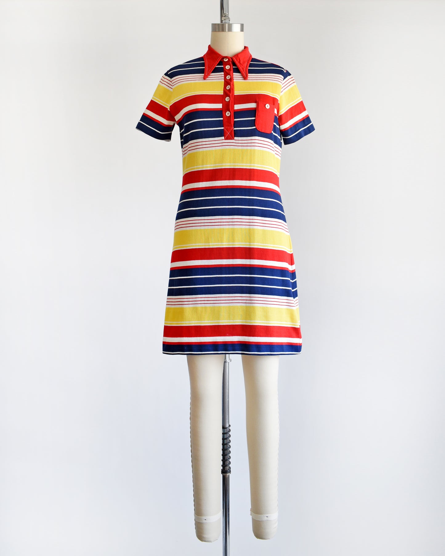 a vintage 1970s red, navy blue, yellow, and white striped dress with a red collar with six buttons down the front and a matching red chest pocket.