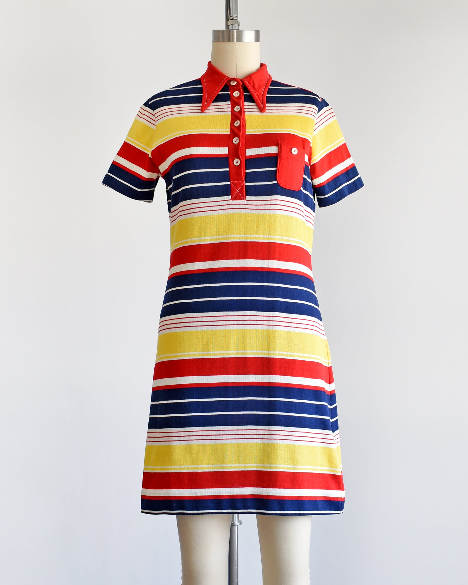 a vintage 1970s red, navy blue, yellow, and white striped dress with a red collar with six buttons down the front and a matching red chest pocket.