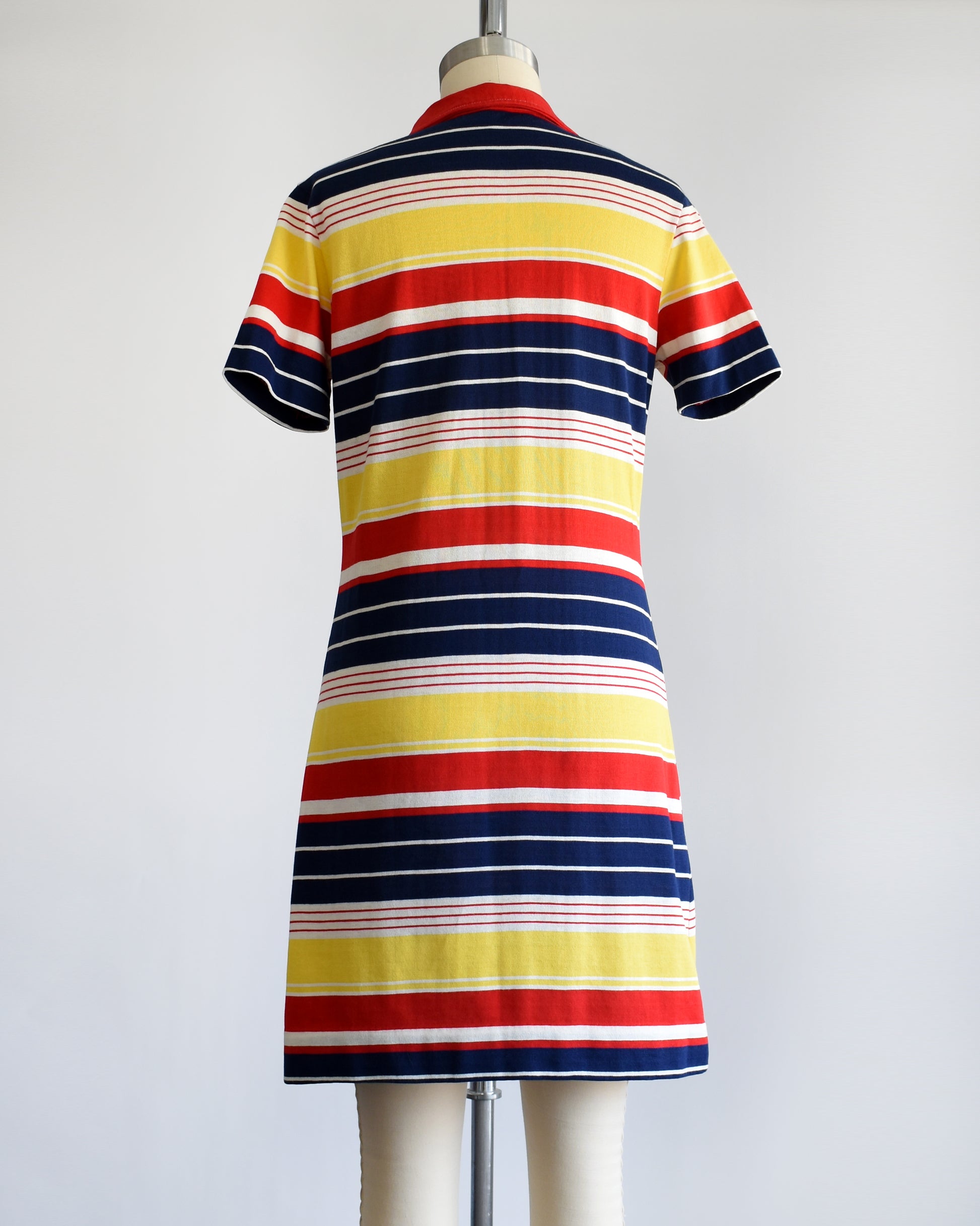 back view of a vintage 1970s red, navy blue, yellow, and white striped dress with a red collar with six buttons down the front and a matching red chest pocket.