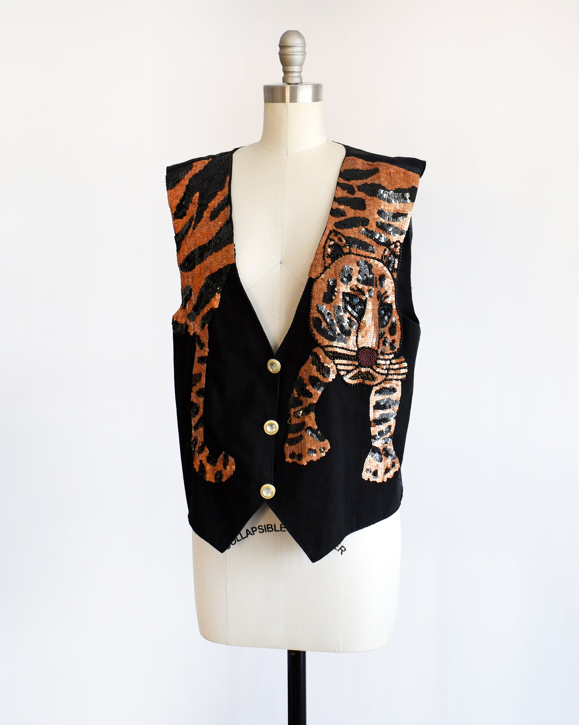side front view of a vintage 1980s black vest with an orange sequin tiger on a mannequin against a white background