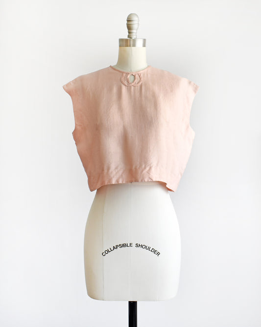 a vintage 1950s/1960s pale pink sleeveless silk crop top displayed on a white dress form mannequin against a plain white background. 